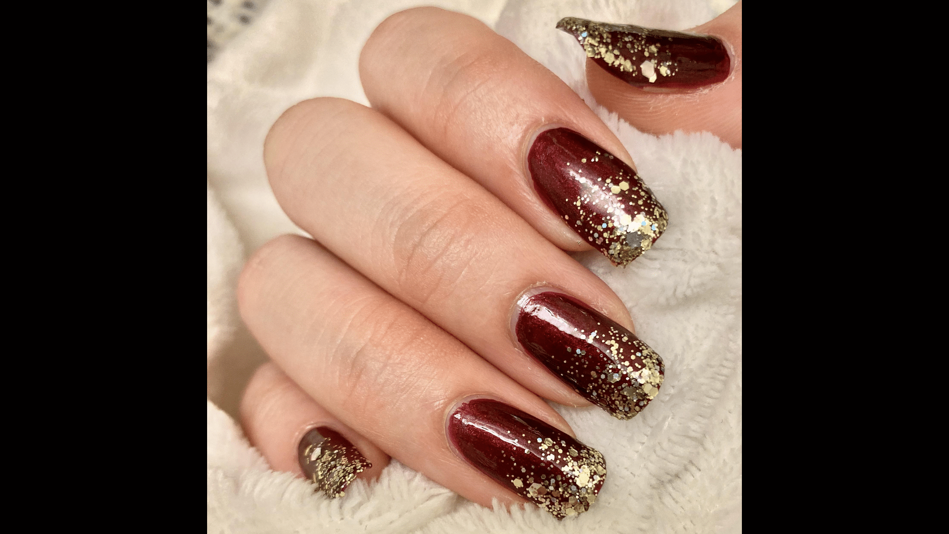 Deep red nails with gold glitter accent