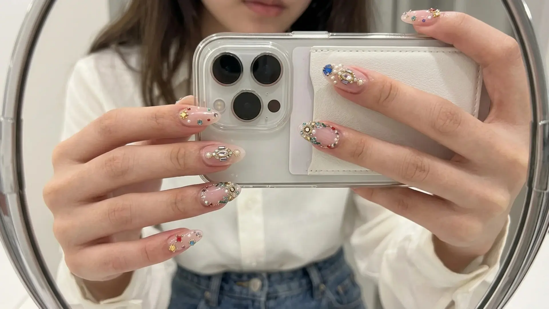 Gemstone and pearl inlay embellished nails holding phone clicking mirror selfie showing spring break nails