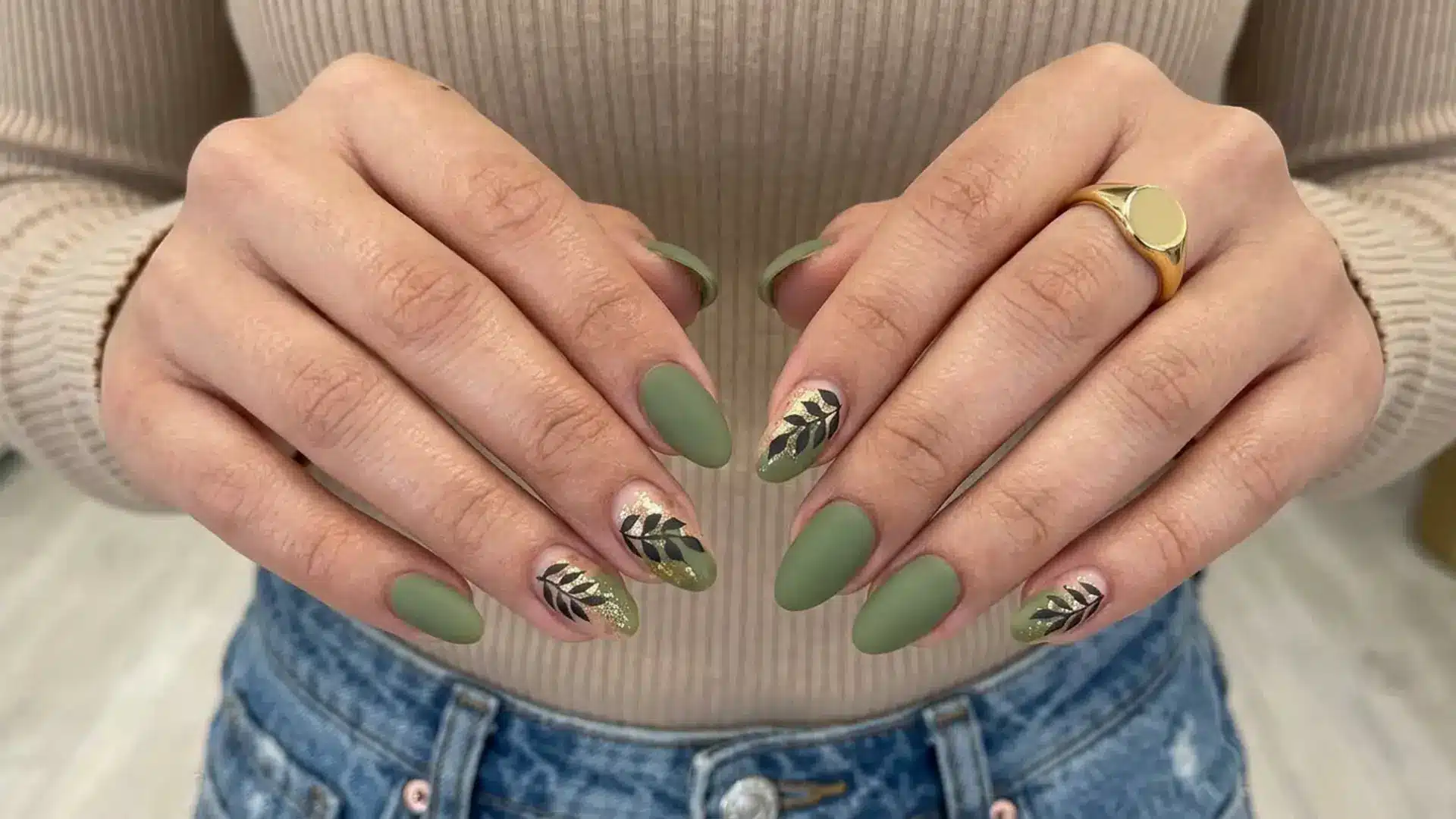 Matte sage green manicure with black palm leaf nail art on almond nails showing trendy sage palm leaf spring break nails