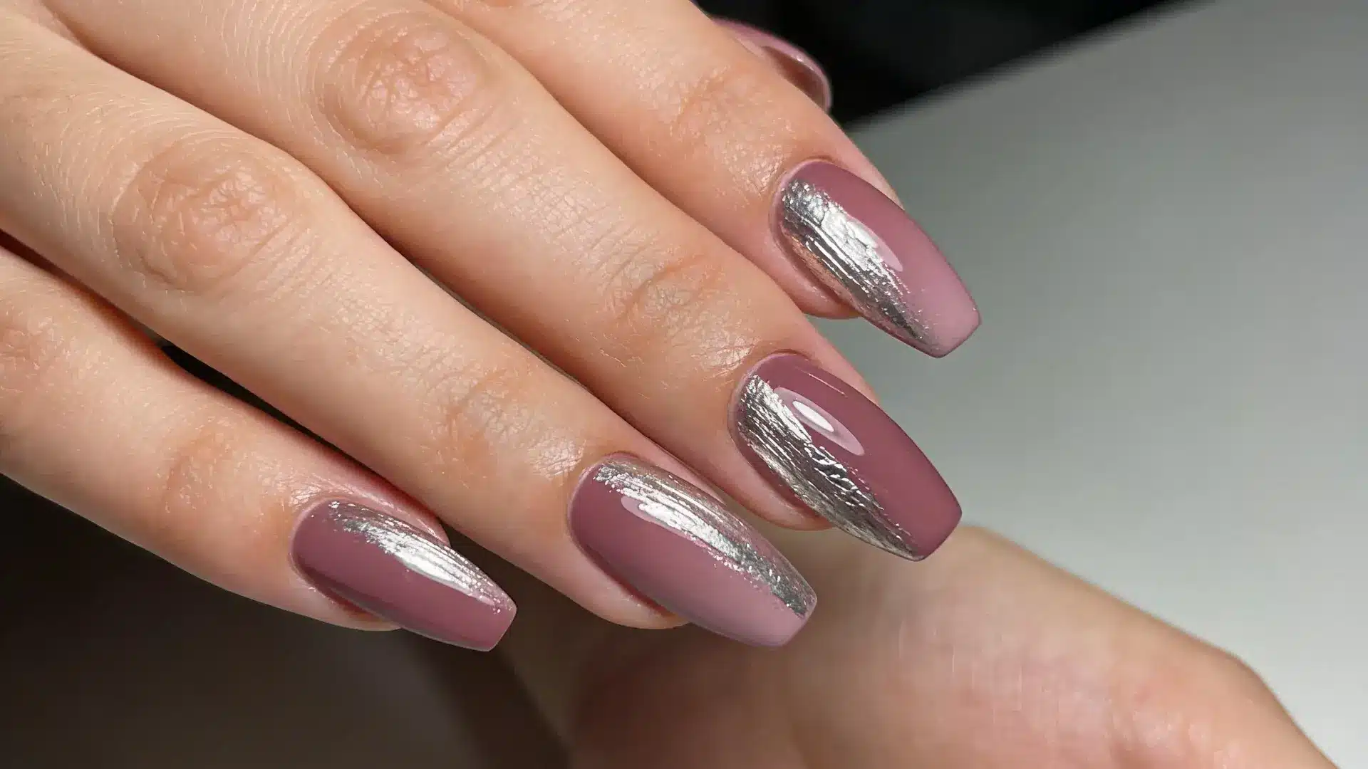 Silver foil placed lightly across a mauve base creates a soft metallic texture in coffin shape nails