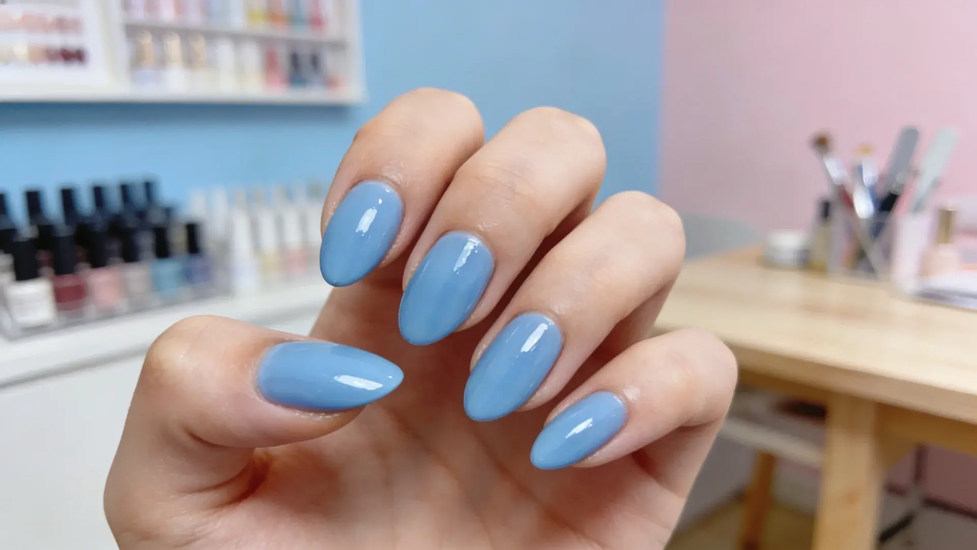 Sky blue glossy almond manicure displayed in nail studio with polish bottles in background