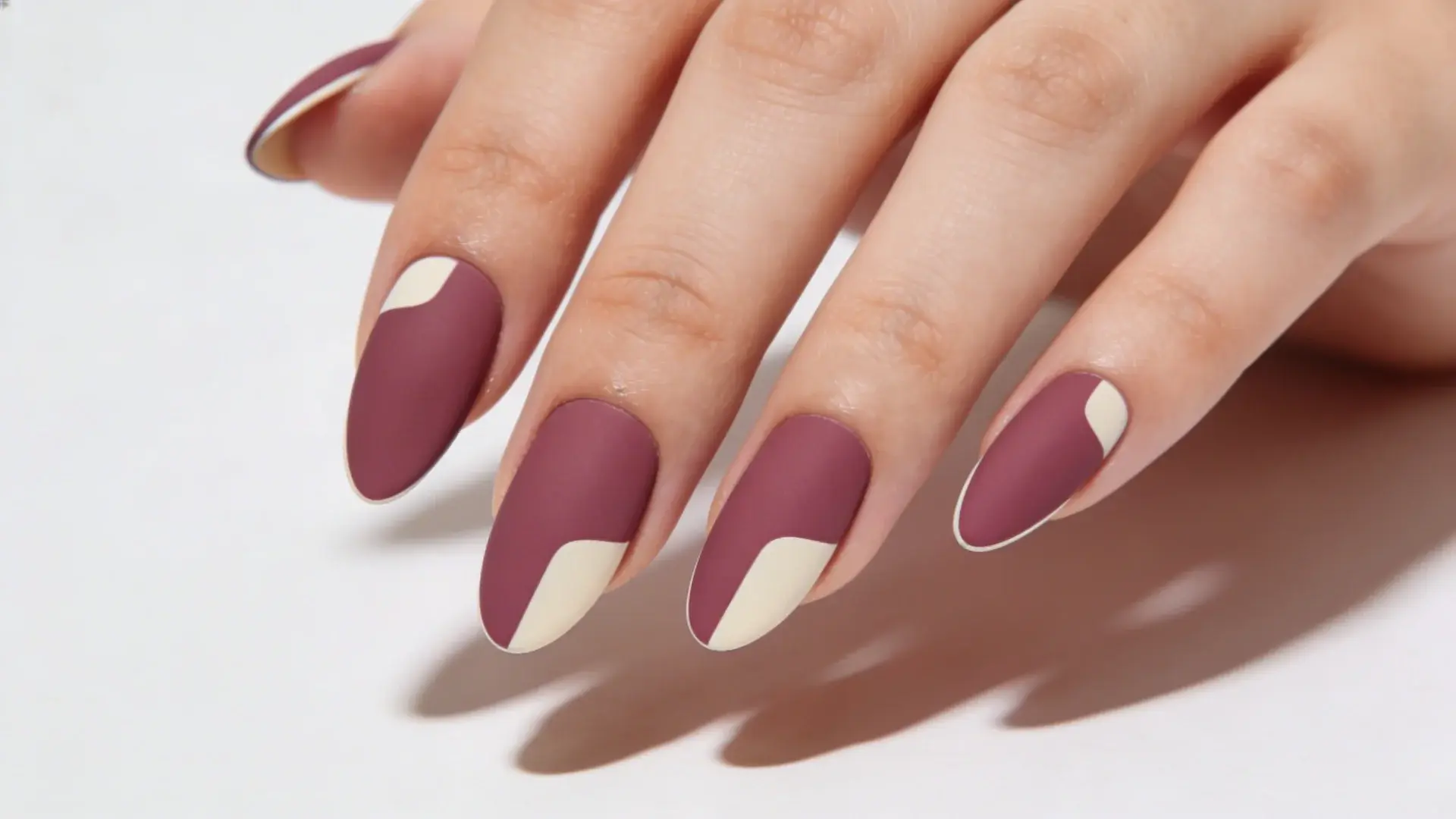 Small areas of natural nail left unpainted create a modern graphic effect in almond shape nails
