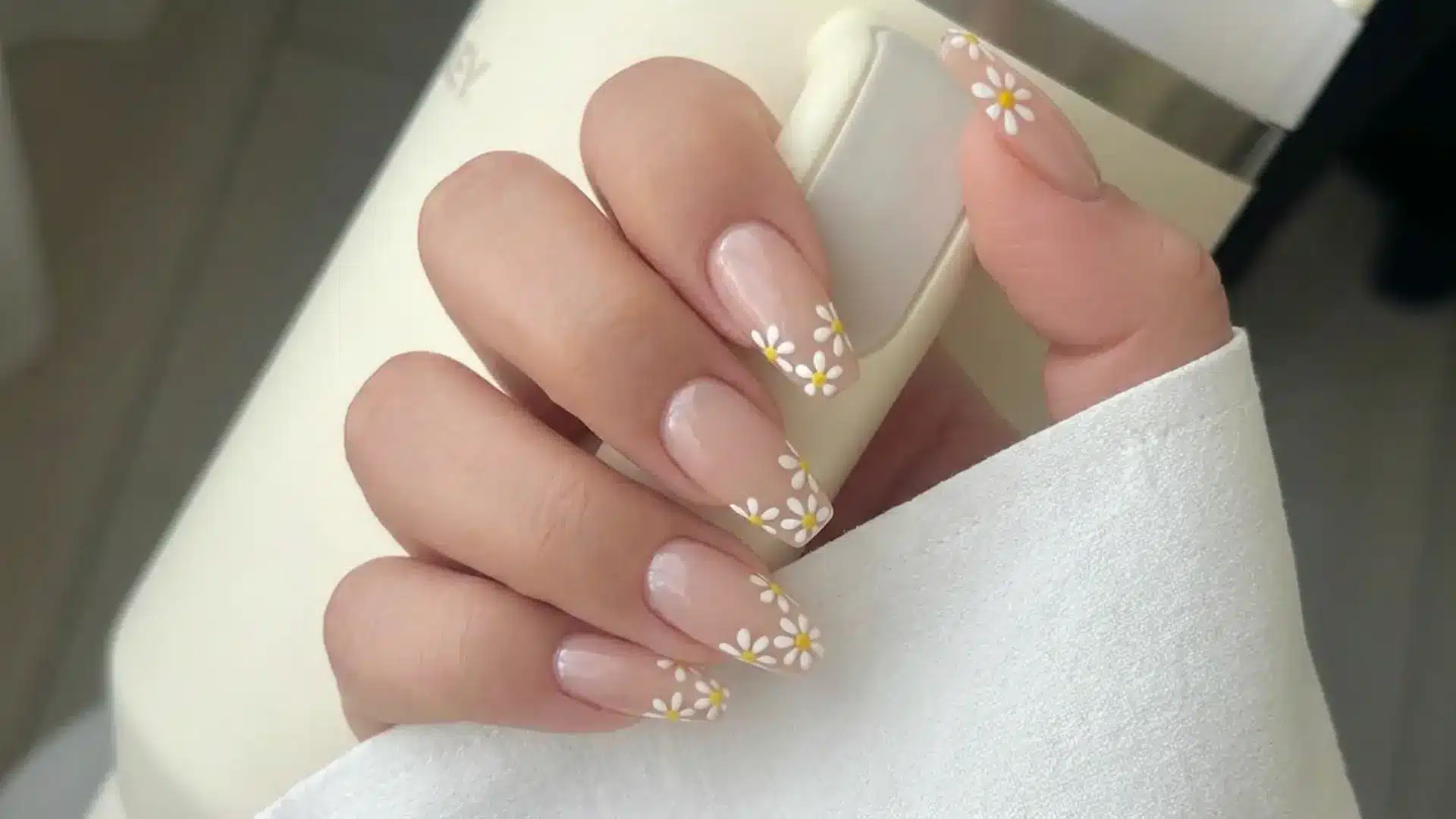 Soft daisy French tip nails design holding a Stanley cup showing spring break nails inspiration