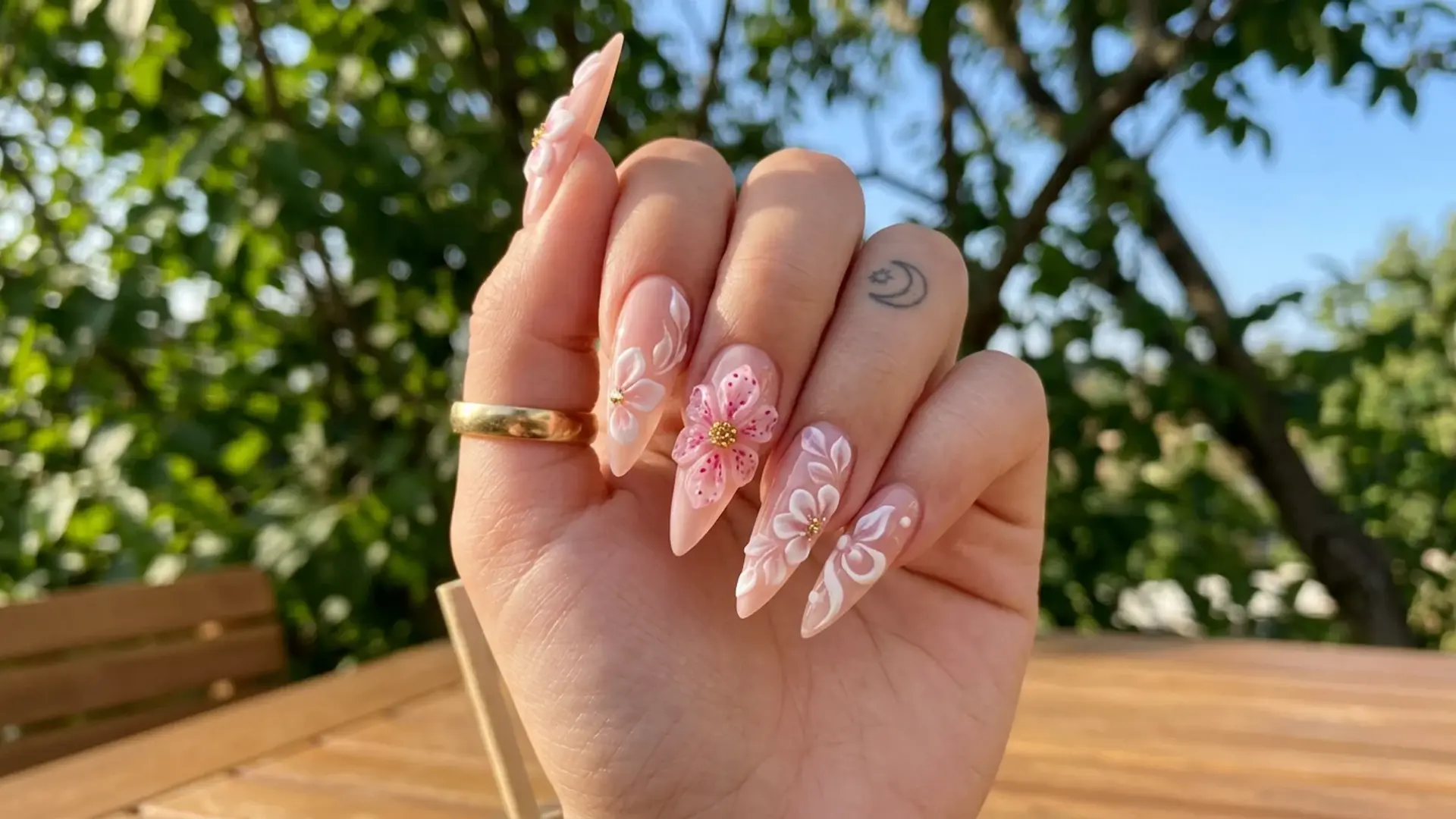 Stiletto nails with detailed pink and white blossoms and raised petals showing delicate 3D floral nail art design