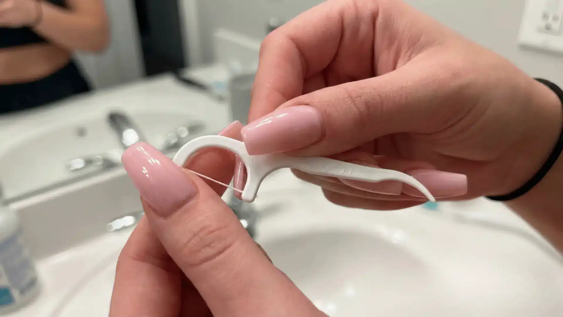 Using dental floss to gently separate acrylic nail from natural nail during DIY acrylic nail removal