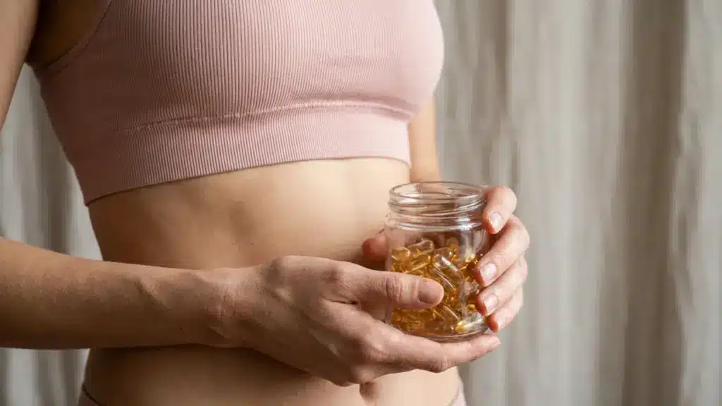 Woman holding a jar of capsules near her abdomen, representing hormonal acne treatment and supplement use