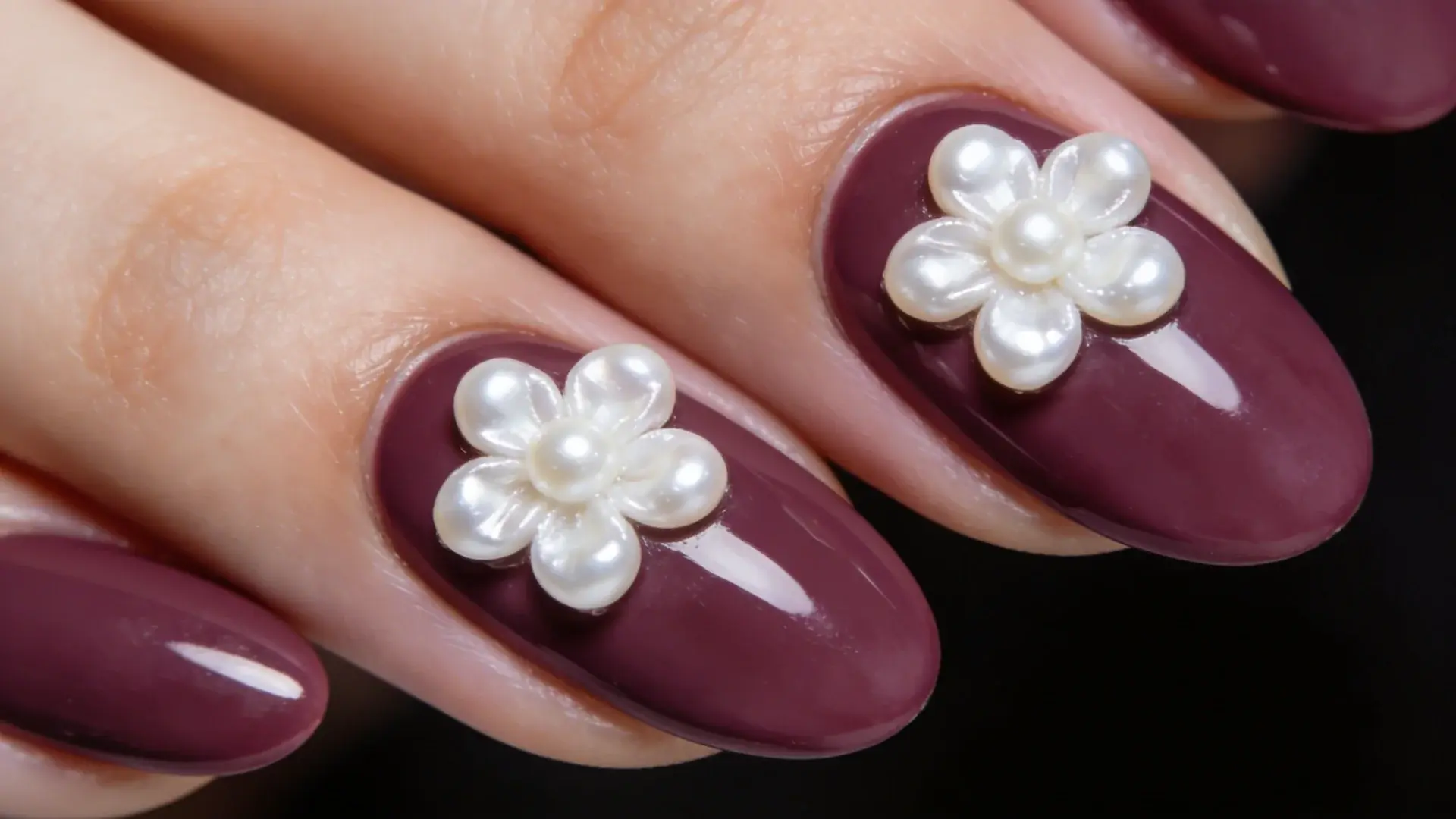 tiny white pearls placed on two nails creating a flower on a oval shape nails