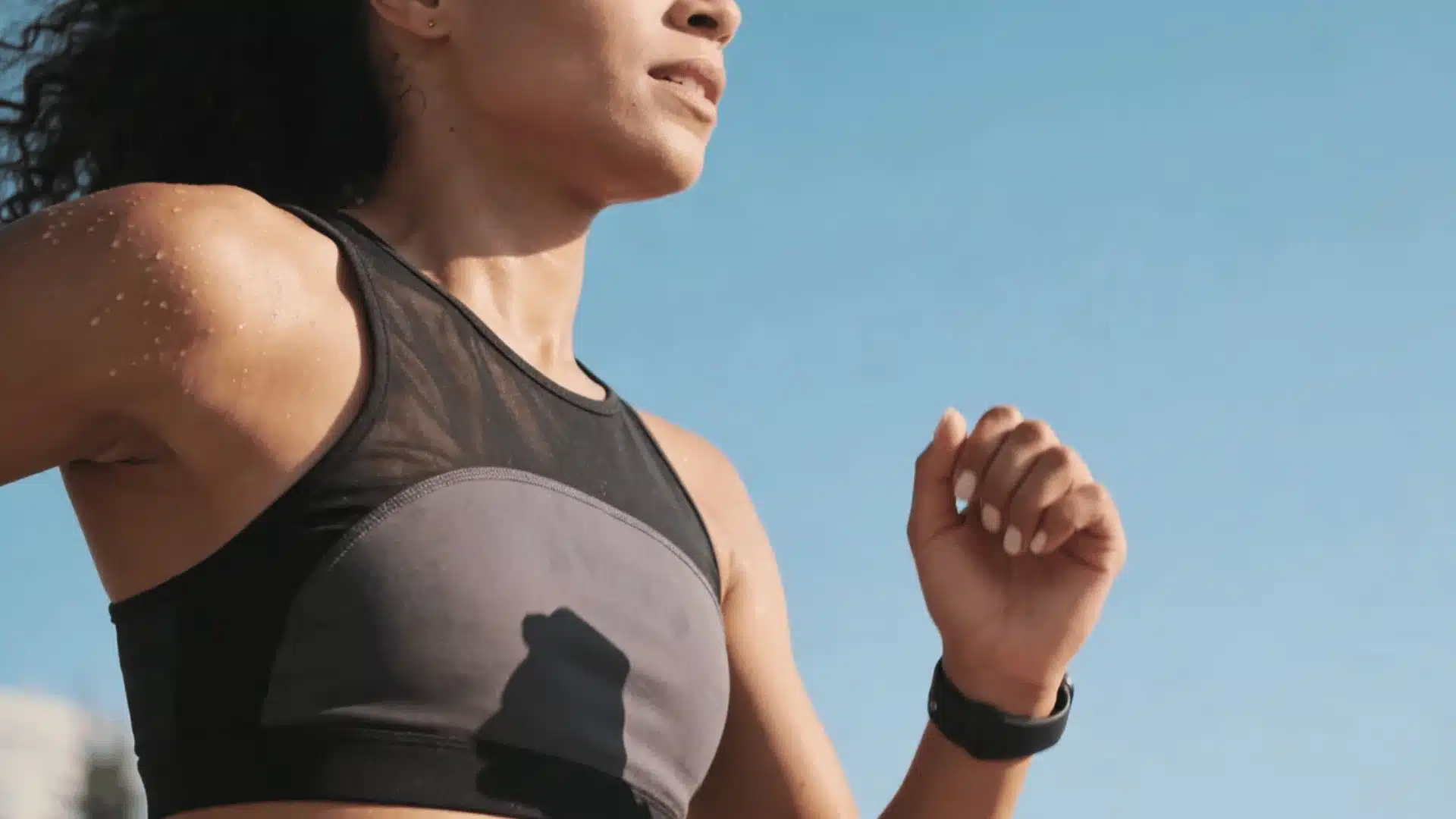 Athletic woman running outdoors in breathable nylon activewear, showing sweat-wicking performance in warm weather