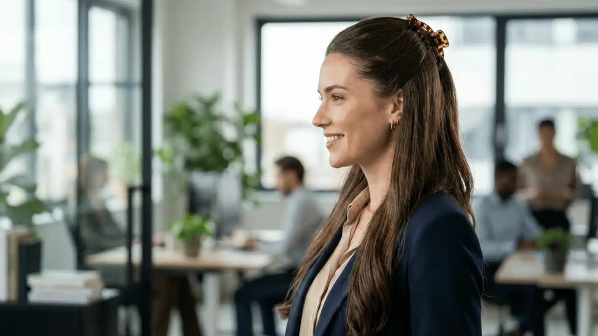 Businesswoman smiling in modern office with coworkers and natural light background