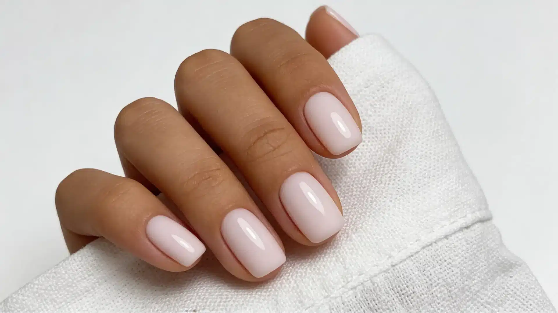 Close up of hand with soft nude dip powder nails showing smooth finish and natural elegant look
