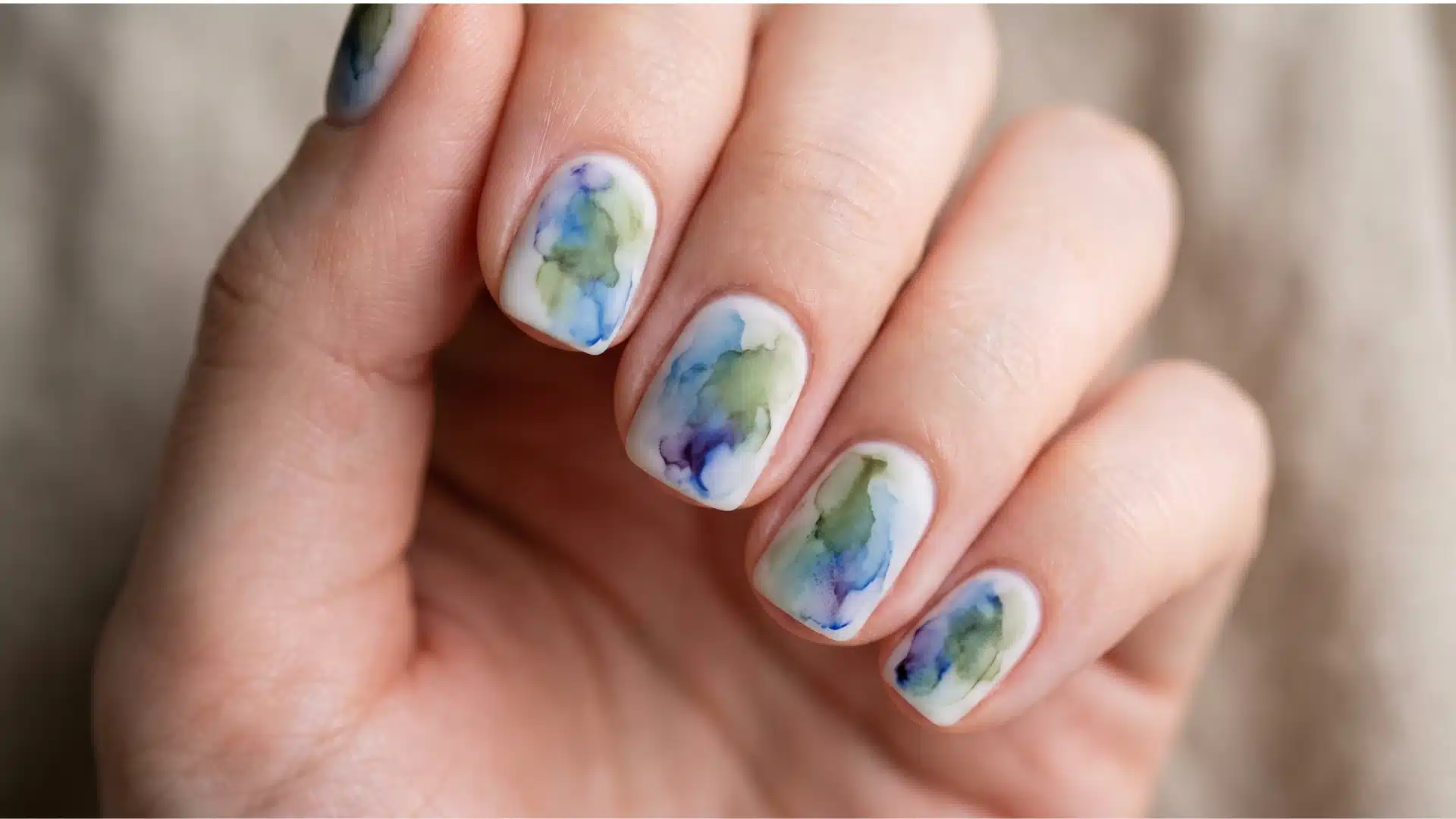 Close-up of ink wash ocean nail art with blue and green diffusion