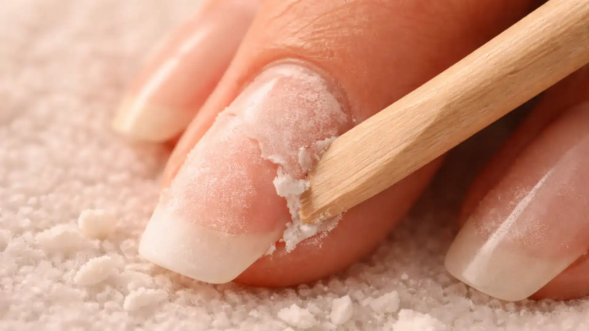 Close-up of nail being cleaned with cuticle stick, removing softened gel residue during manicure process