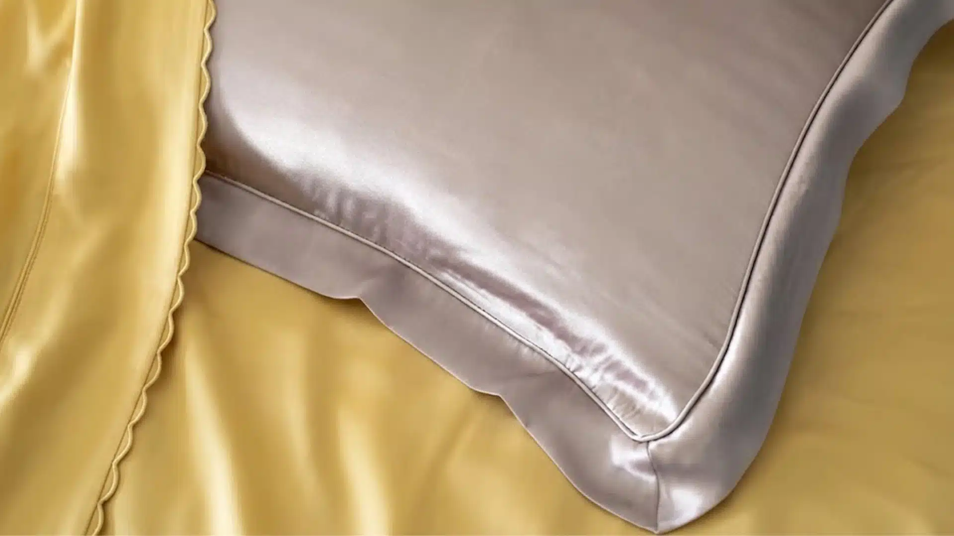Close-up of smooth silk pillowcase on bed with soft sheen and gold bedding, highlighting texture and finish
