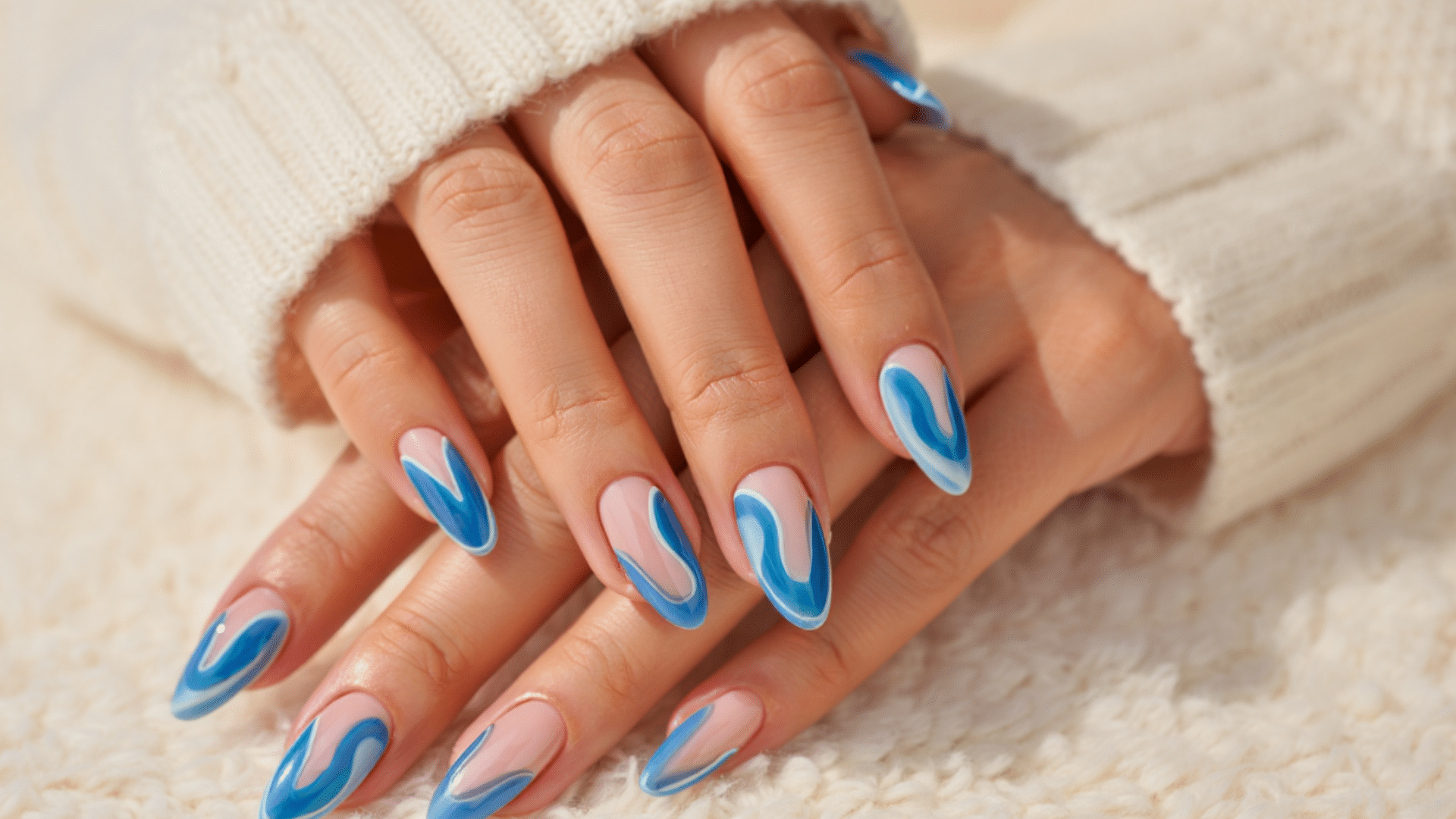 Colourful glossy almond-shaped nail art on feminine hand inside a dim luxury nail salon with warm ambient lighting and blurred background. (4)