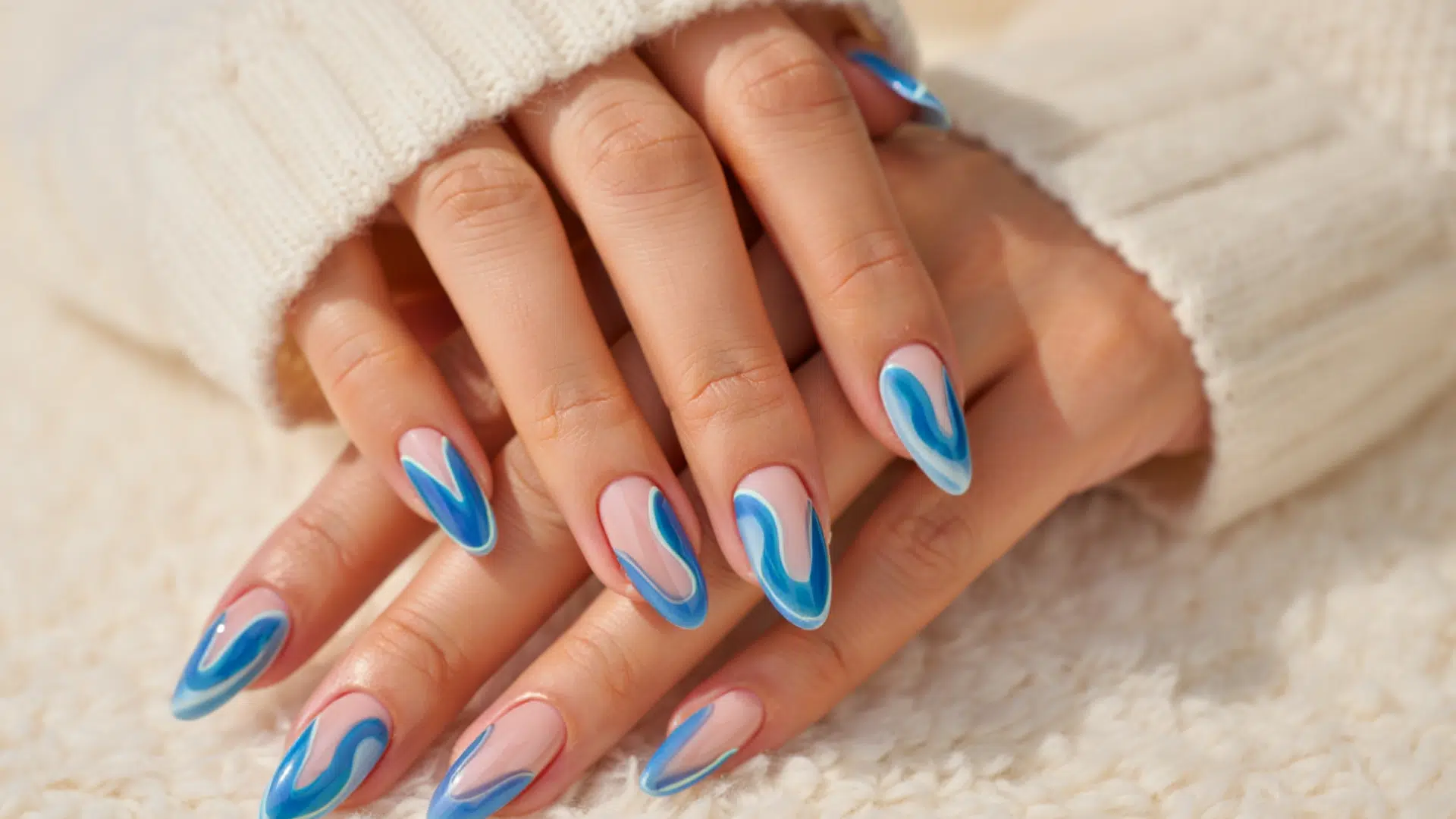 Colourful glossy almond-shaped nail art on feminine hand inside a dim luxury nail salon with warm ambient lighting and blurred background. (4)