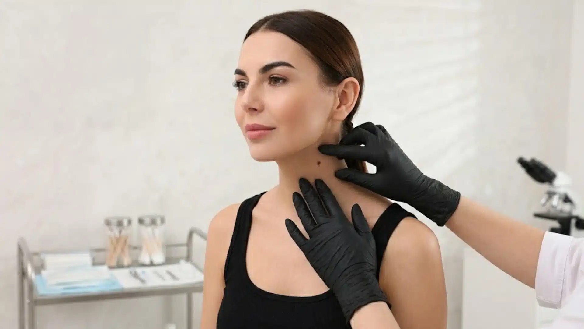 Dermatologist examining moles on a woman’s neck during a skin check in a clinical setting