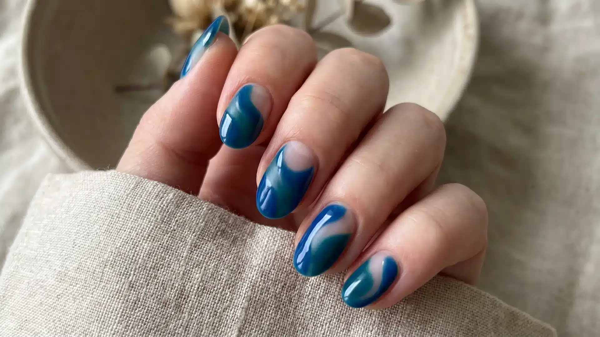 Glossy teal nails with flowing bare cuticle arcs creating organic negative space
