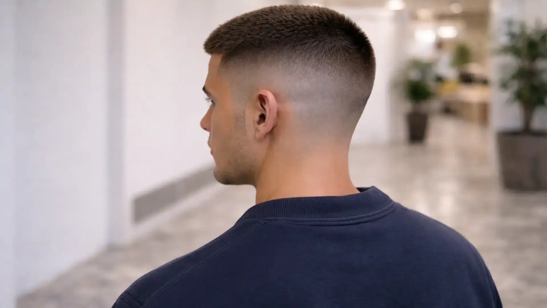 Man with low fade buzz cut hairstyle shown from back highlighting gradual taper and clean neckline finish
