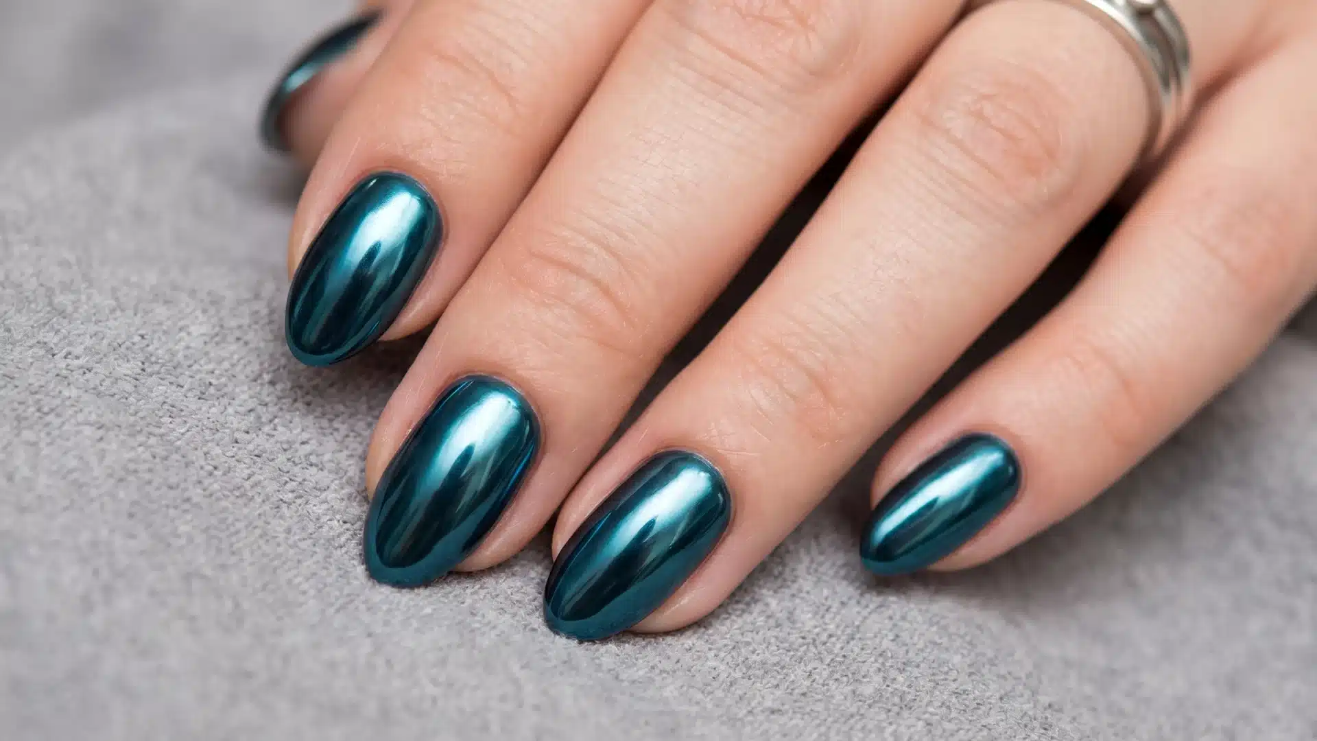Metallic teal chrome nails with glossy mirror finish on almond shape