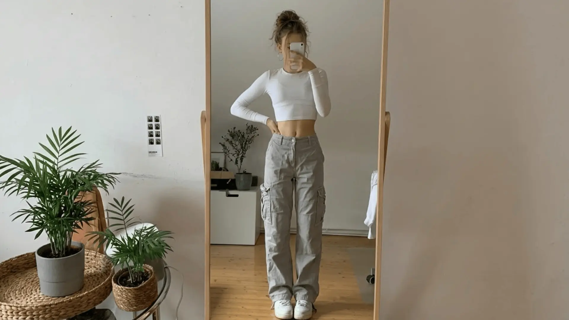 Mirror selfie outfit with white crop top and light grey cargo pants styled with sneakers minimalist room