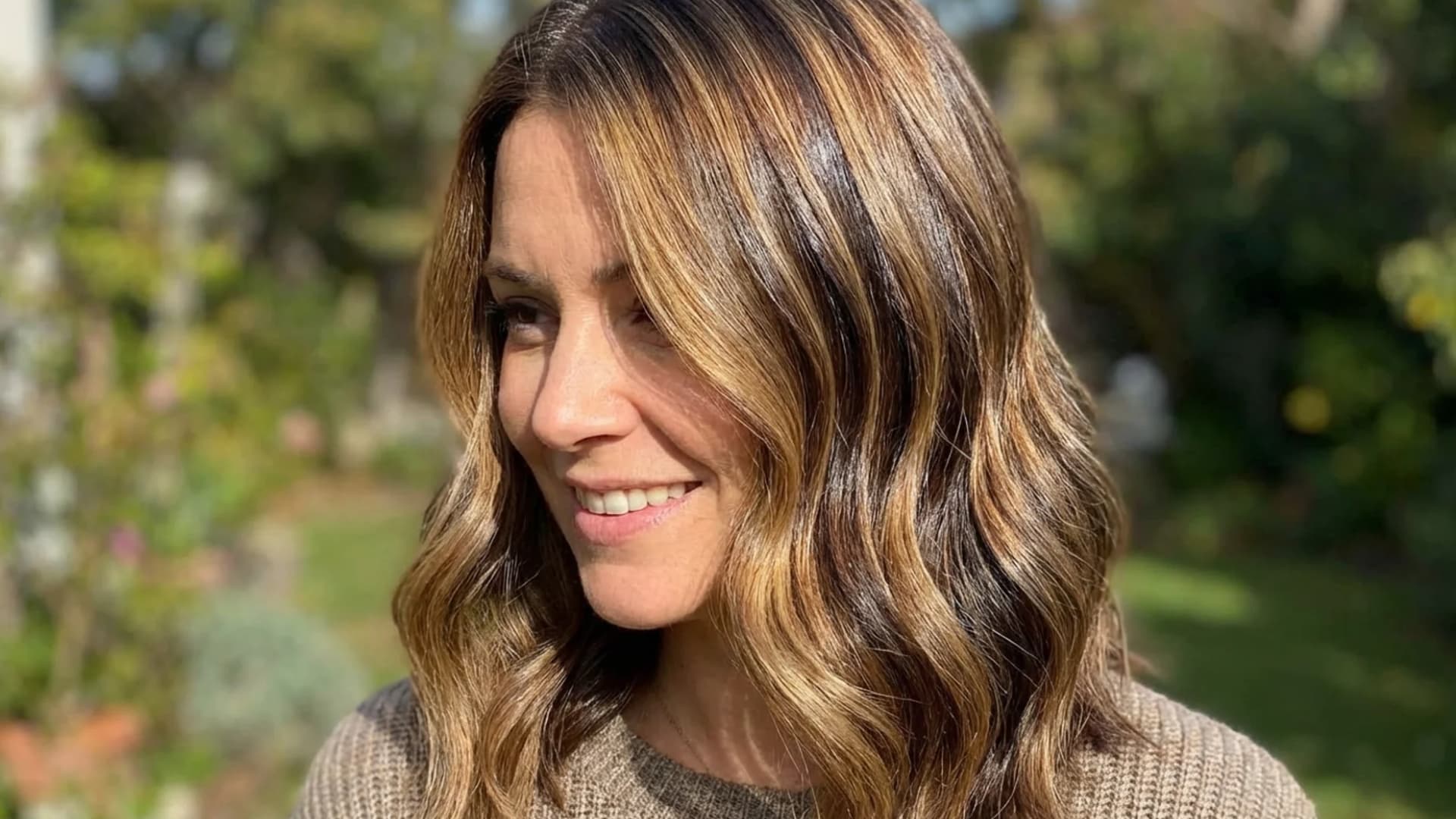 Portrait of a woman with lowlights in her hair, darker strands blended into lighter base color, added depth and richness