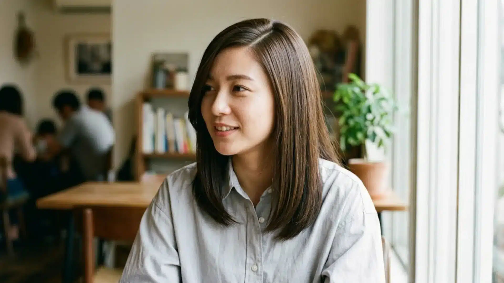 Professional woman with shoulder length hair sitting indoors near window in relaxed office setting