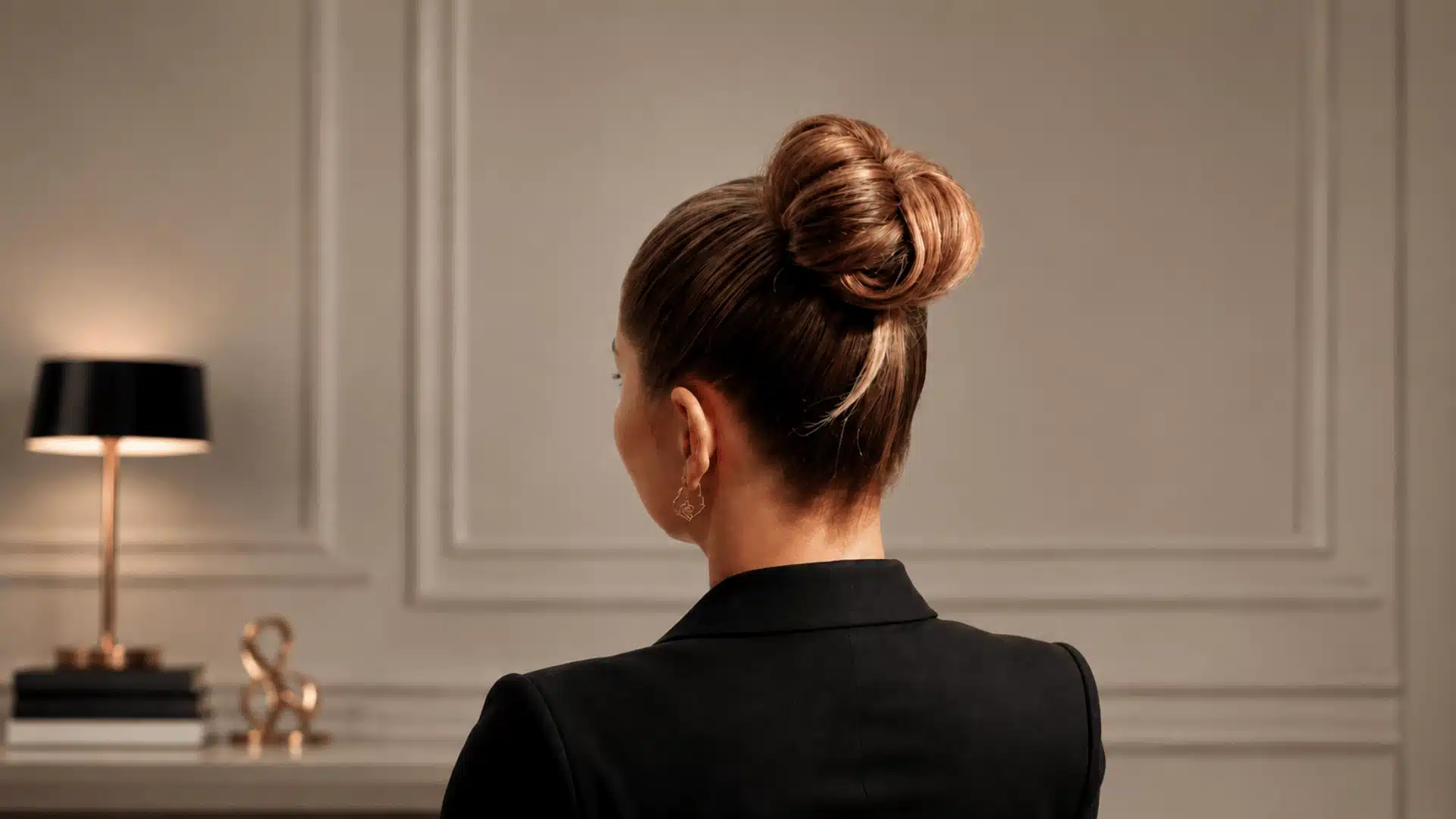Rear view of a woman with a sleek, polished high bun in a professional setting