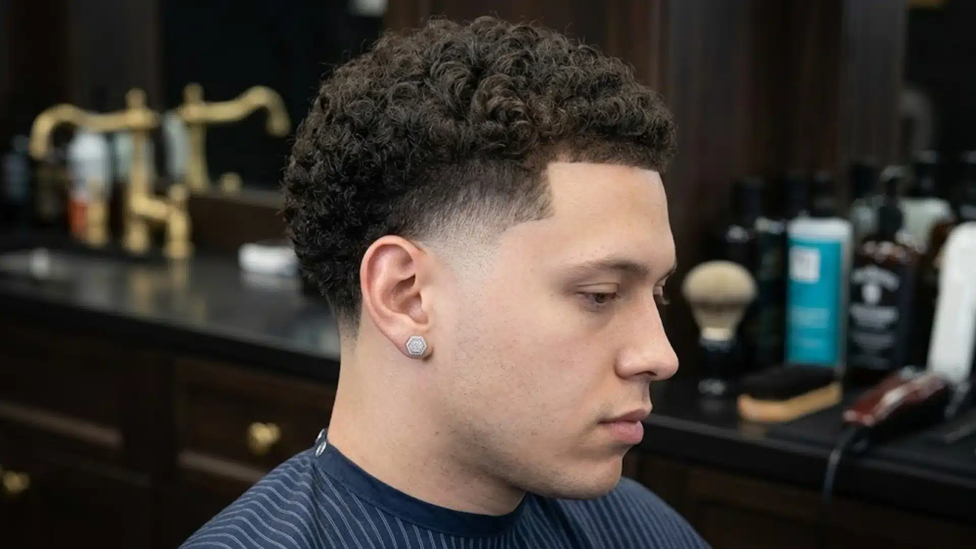 Temple fade haircut with curly textured top and sharp blended sides inside a modern barbershop