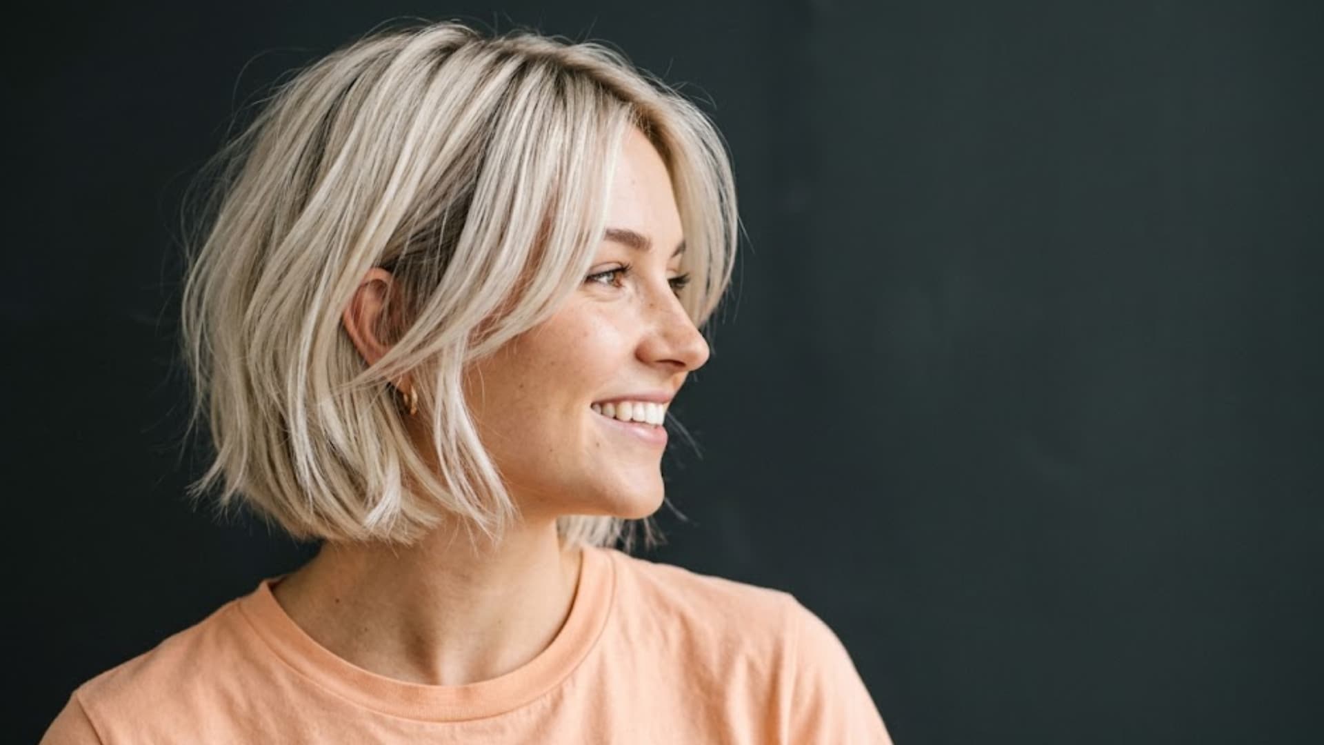 Woman with a short, layered blonde bob haircut, styled with soft volume and slightly tousled texture