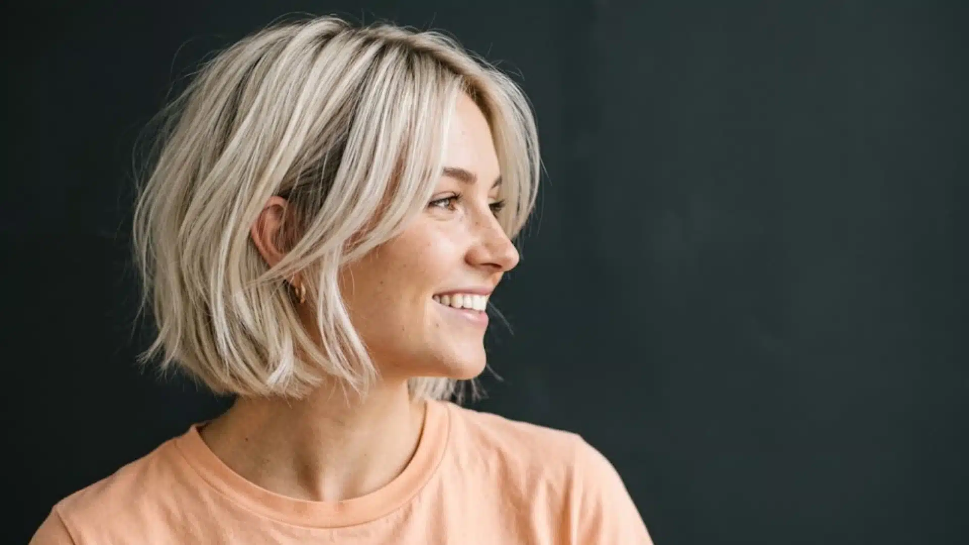 Woman with a short, layered blonde bob haircut, styled with soft volume and slightly tousled texture