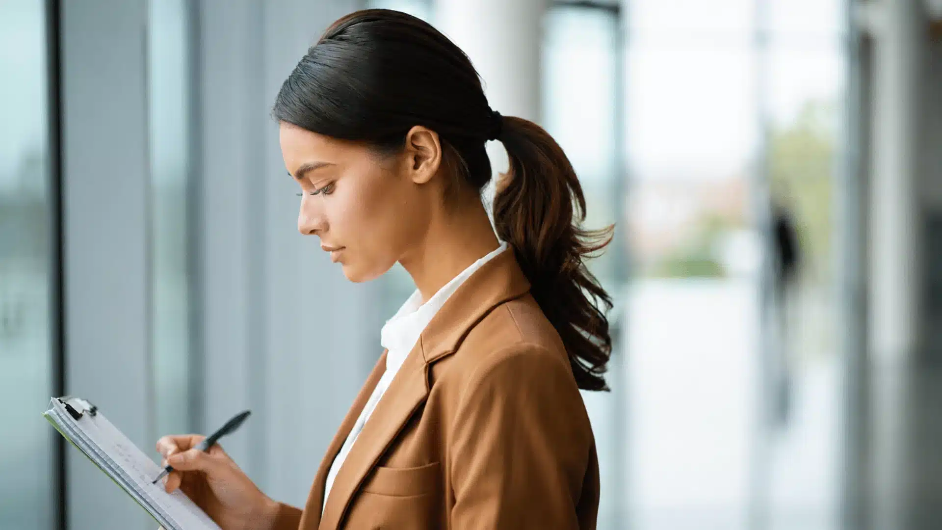 Woman with low twisted ponytail, writing notes