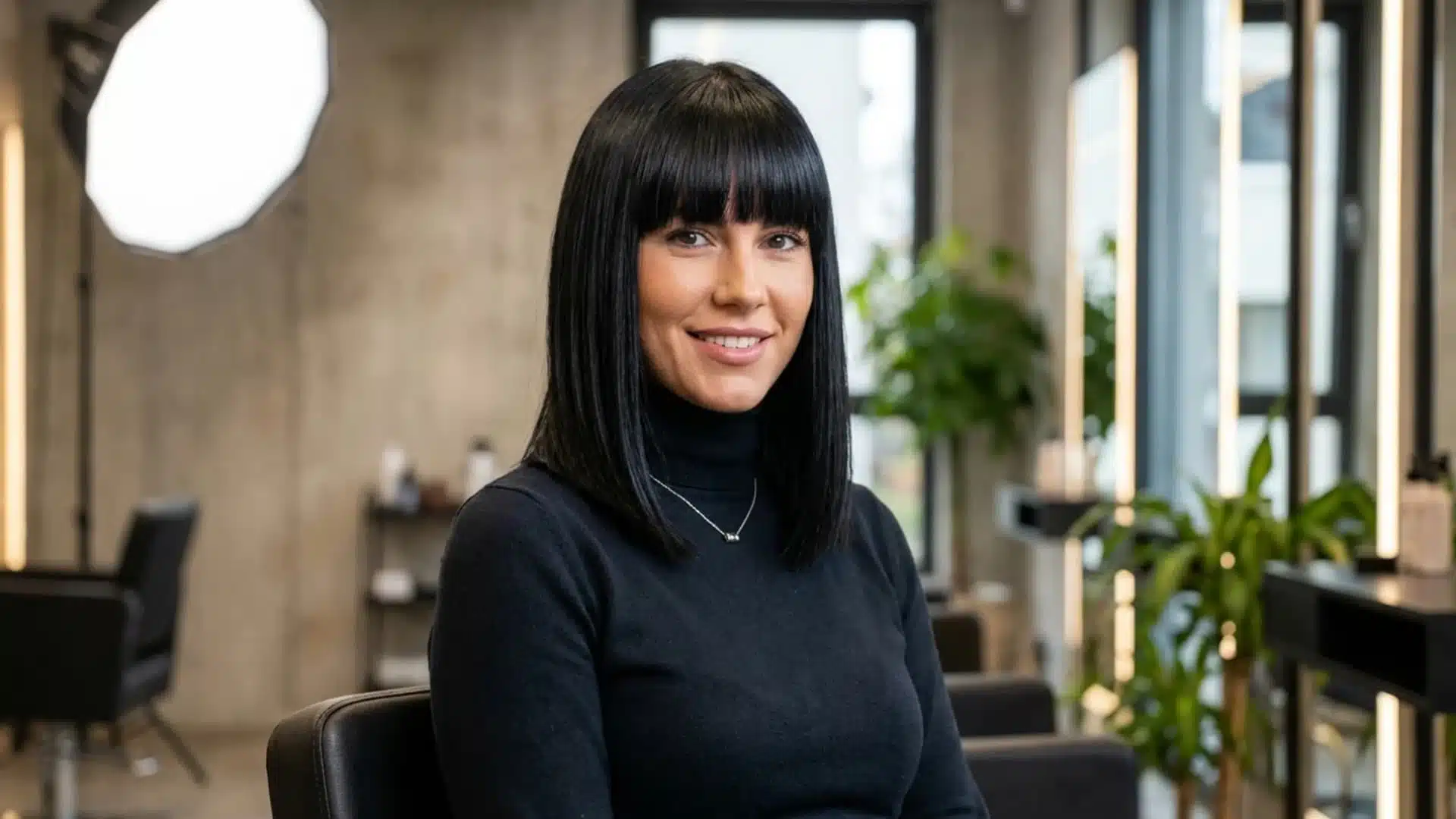 Woman with Shoulder Length Cut with Blunt Bangs, layered dark brown hair styled in a smooth blowout