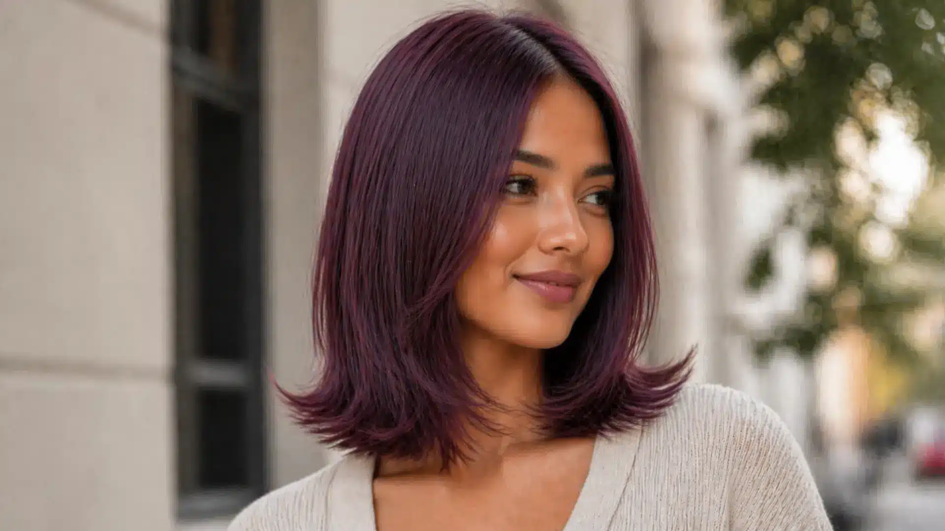 Woman with shoulder length layered purple hair, soft flipped ends, smooth texture and natural outdoor lighting