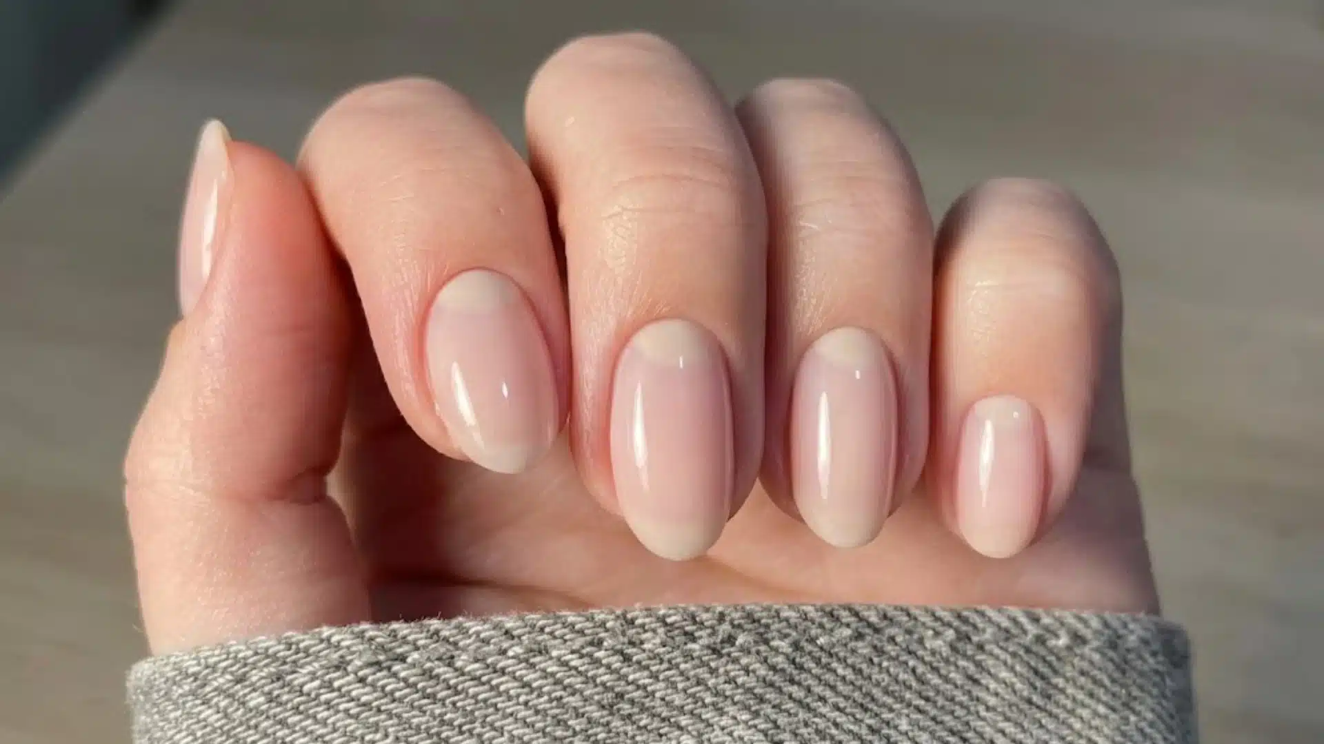 A hand showing a pristine, minimalist neutral russian manicure with perfectly manicured cuticles.