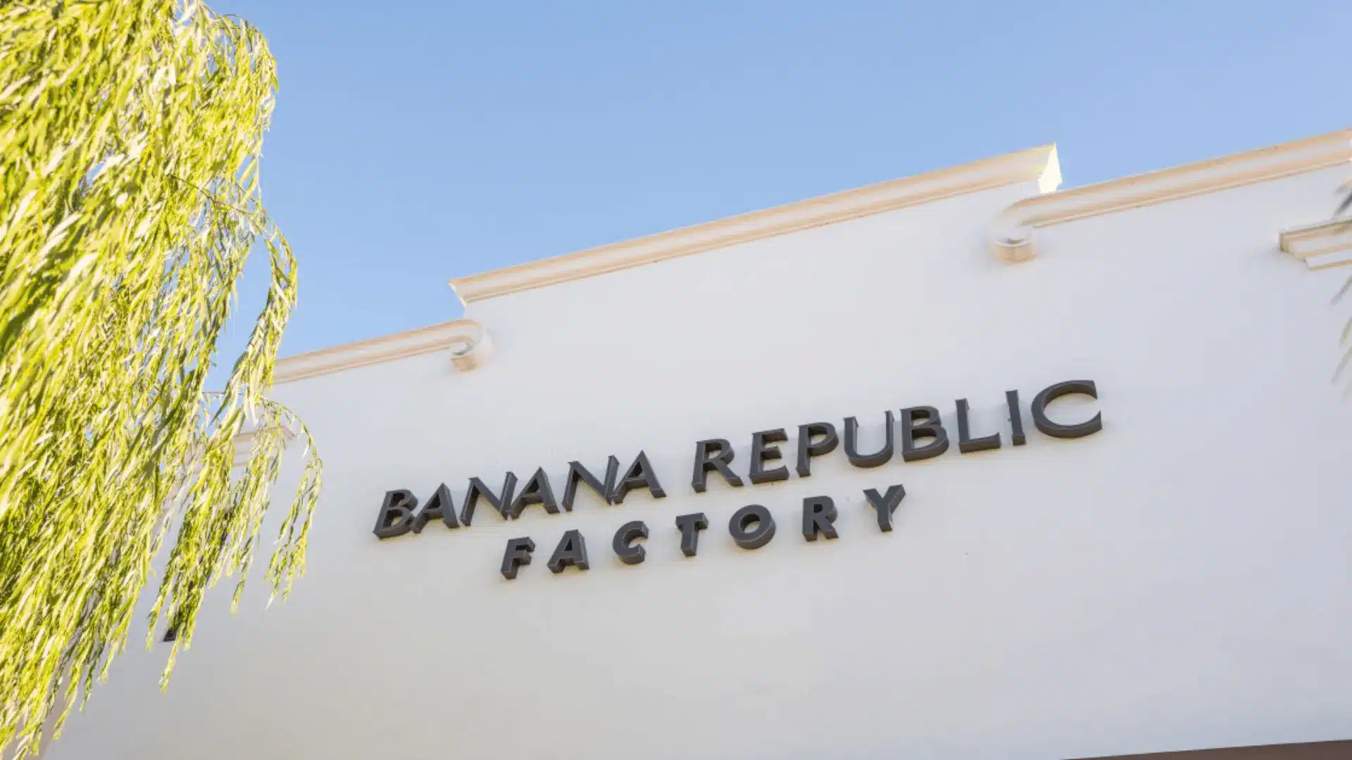 Banana Republic Factory store exterior with logo signage on building under clear sky and palm tree view