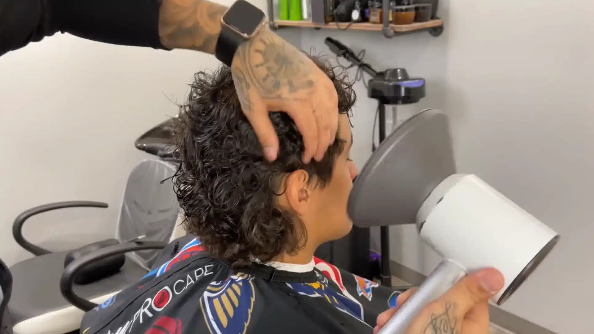 Barber blow dries damp curly hair and debulks the sides to shape a cleaner layered haircut finish