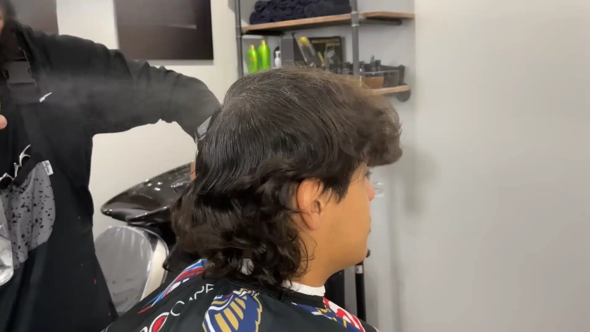 Barber dampens long wavy hair before dividing it into three sections for a clean haircut setup guide