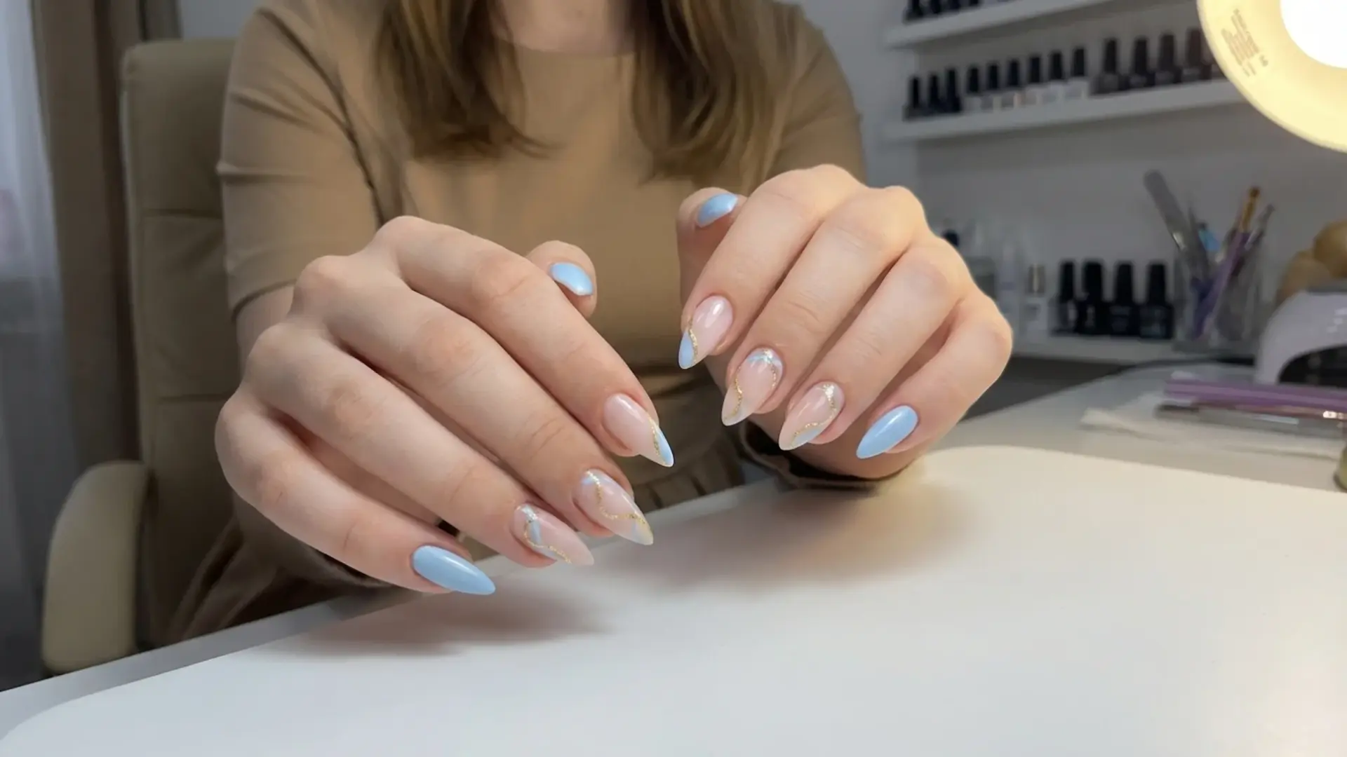 Blue manicure nail inspiration on almond nails displayed at nail salon table