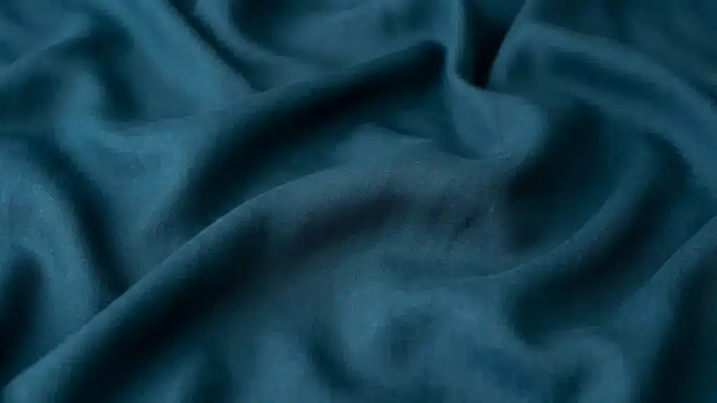 Blue viscose fabric with a soft texture and smooth flowing folds in close up view