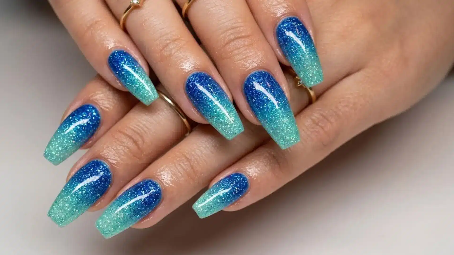Blue glitter ombre coffin nails with sparkle finish, bold acrylic manicure style for party or evening look