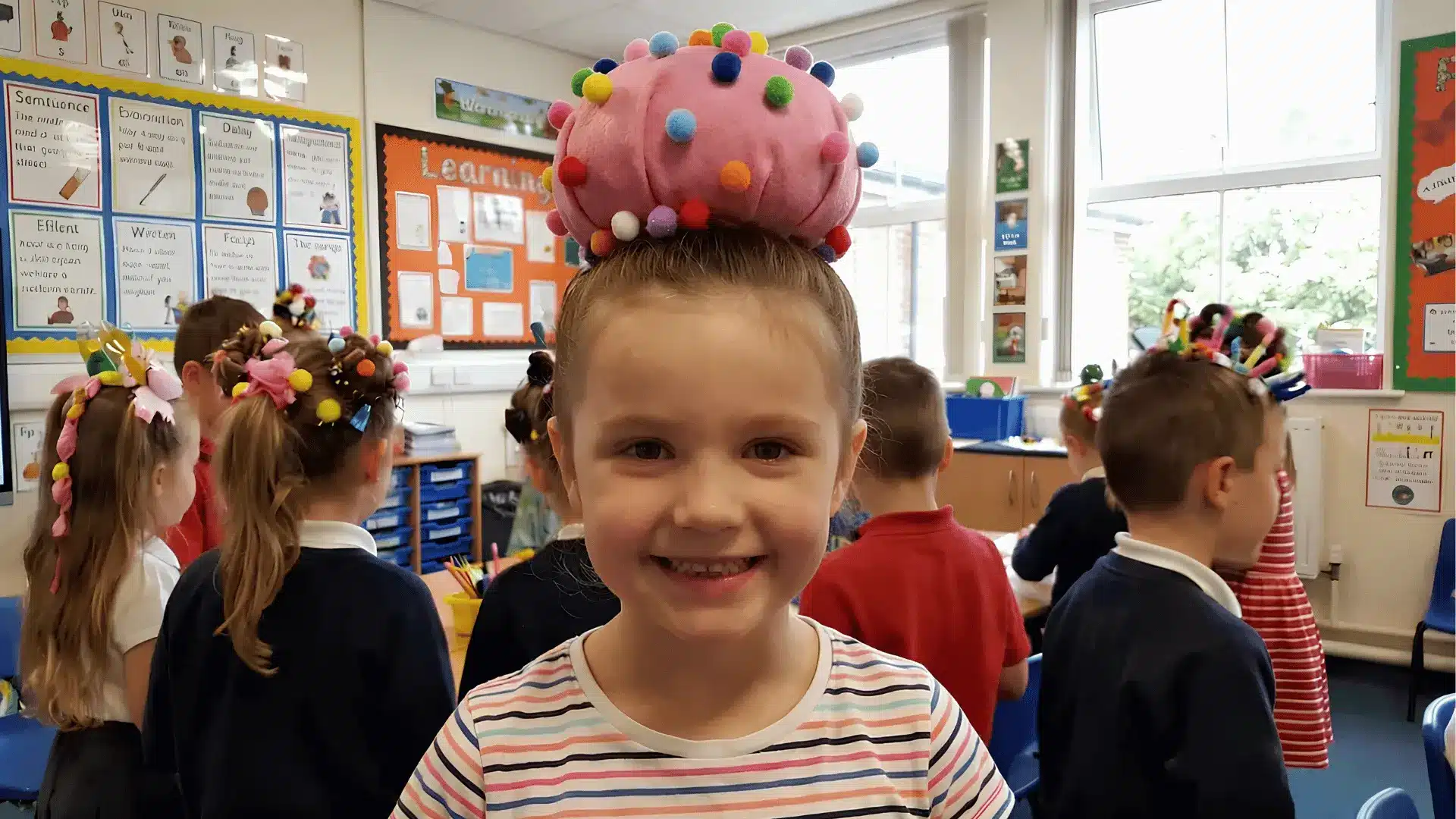 Child with donut bun hairstyle smiling in classroom