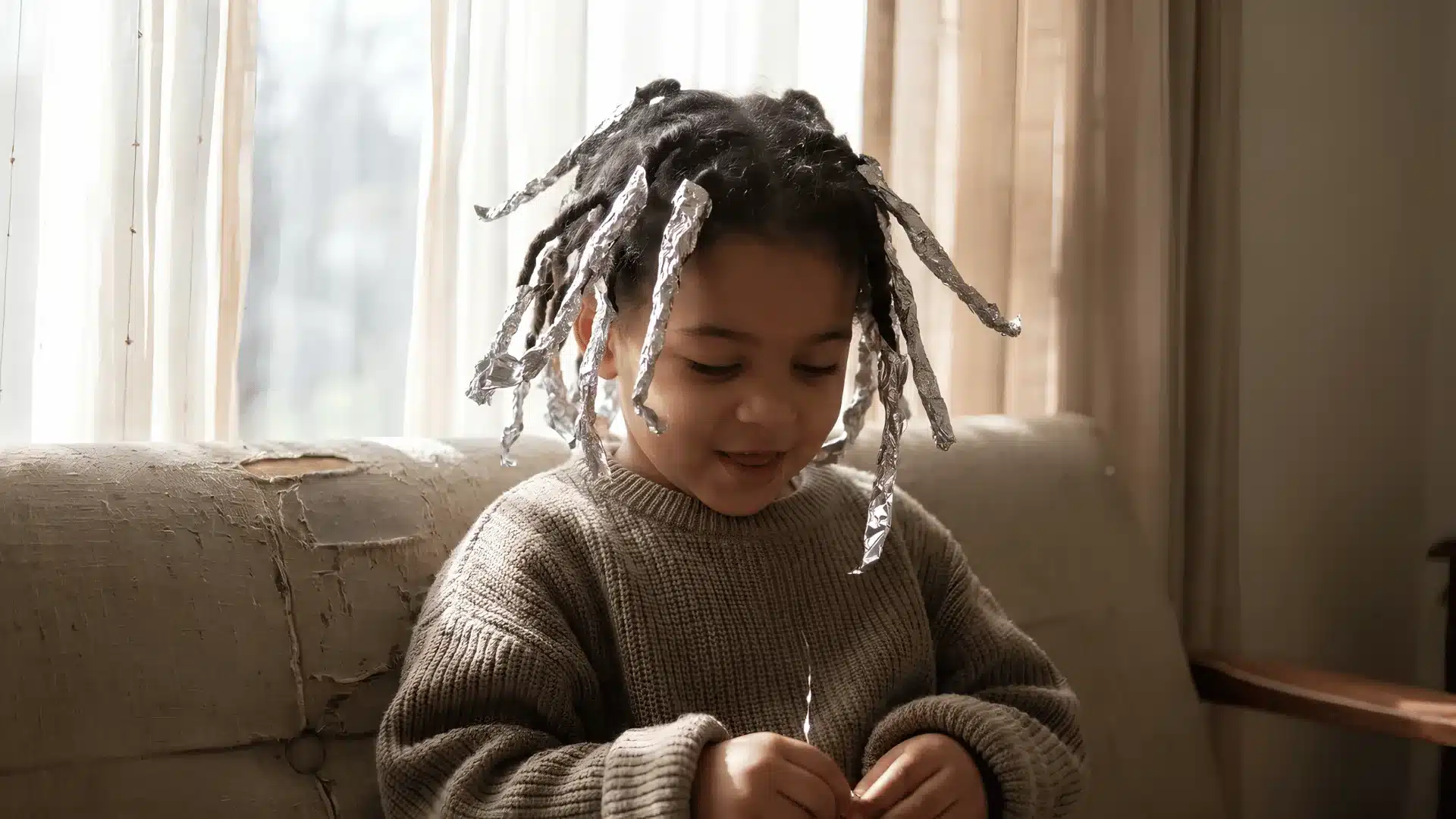 Child with foil strands in hair smiling while sitting indoors