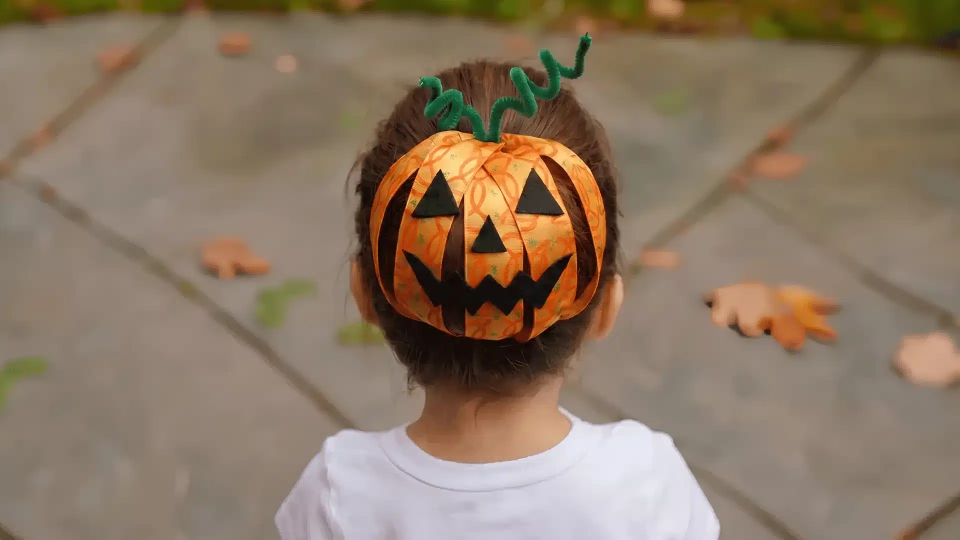 Child with pumpkin hairstyle for Halloween standing outdoors