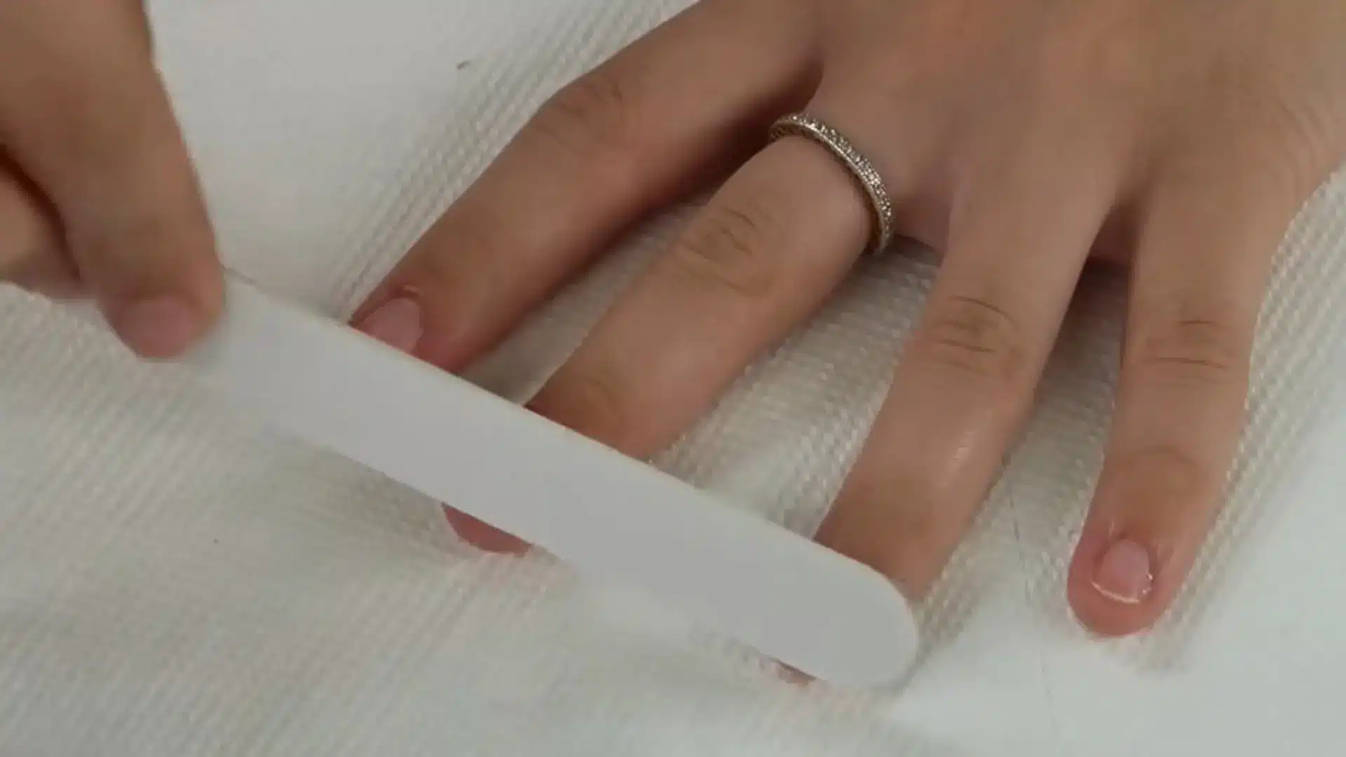 Close up of hand filing nails with a nail file during at home manicure tutorial on YouTube interface