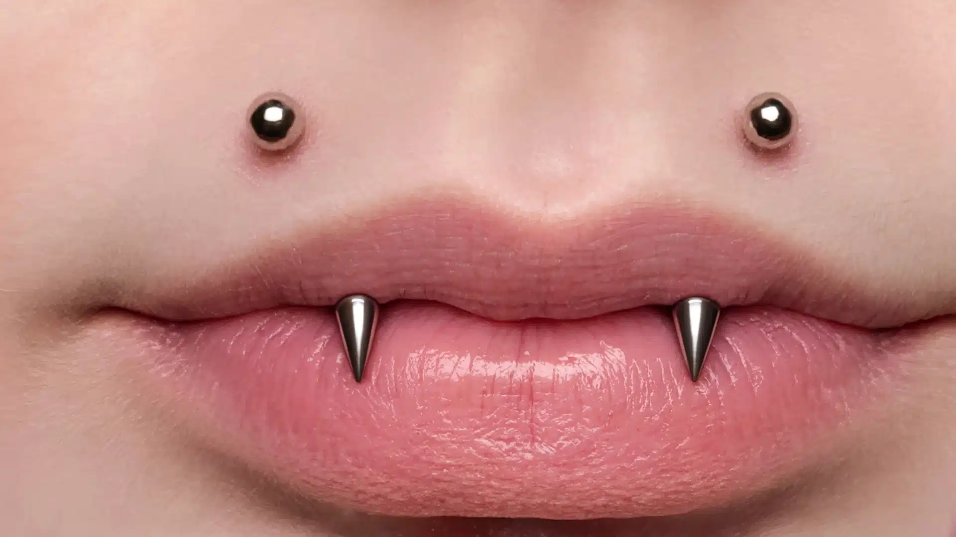 Close-up of an angel fangs lip piercing featuring silver studs above the upper lip and spikes resting over the lower lip