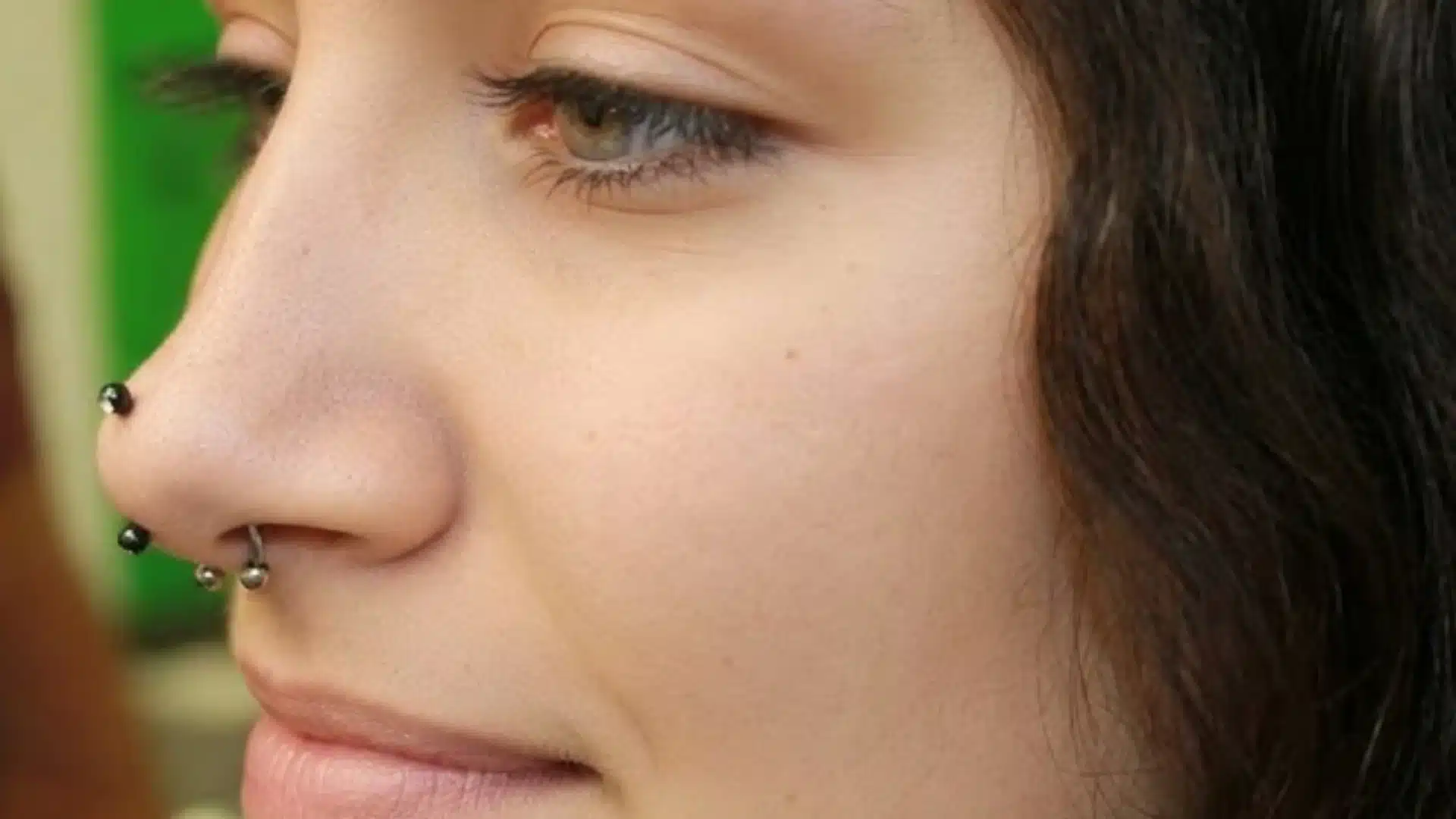 Close-up of a person's profile in image_07d06d.jpg showing multiple nose piercings, including a septum and nostril