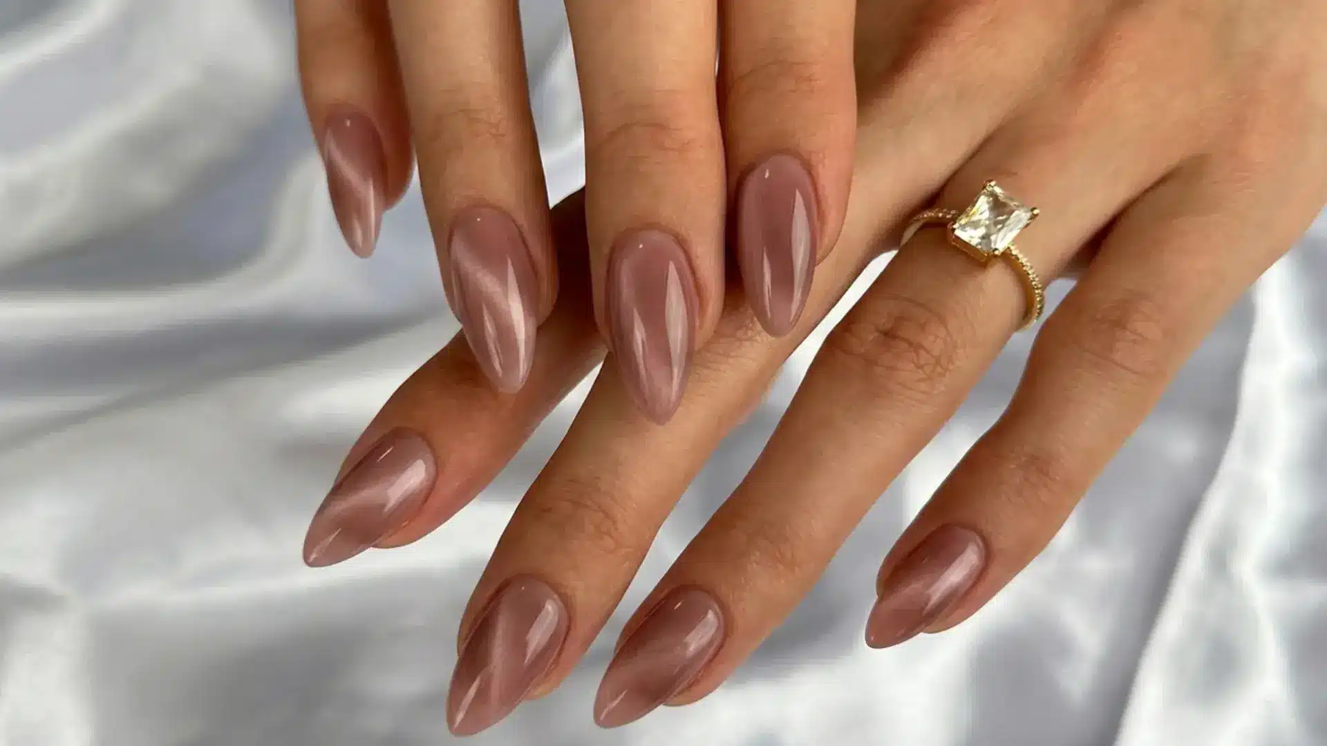 Close up of glossy jelly nails in sheer brown tone on almond shaped nails with smooth translucent finish