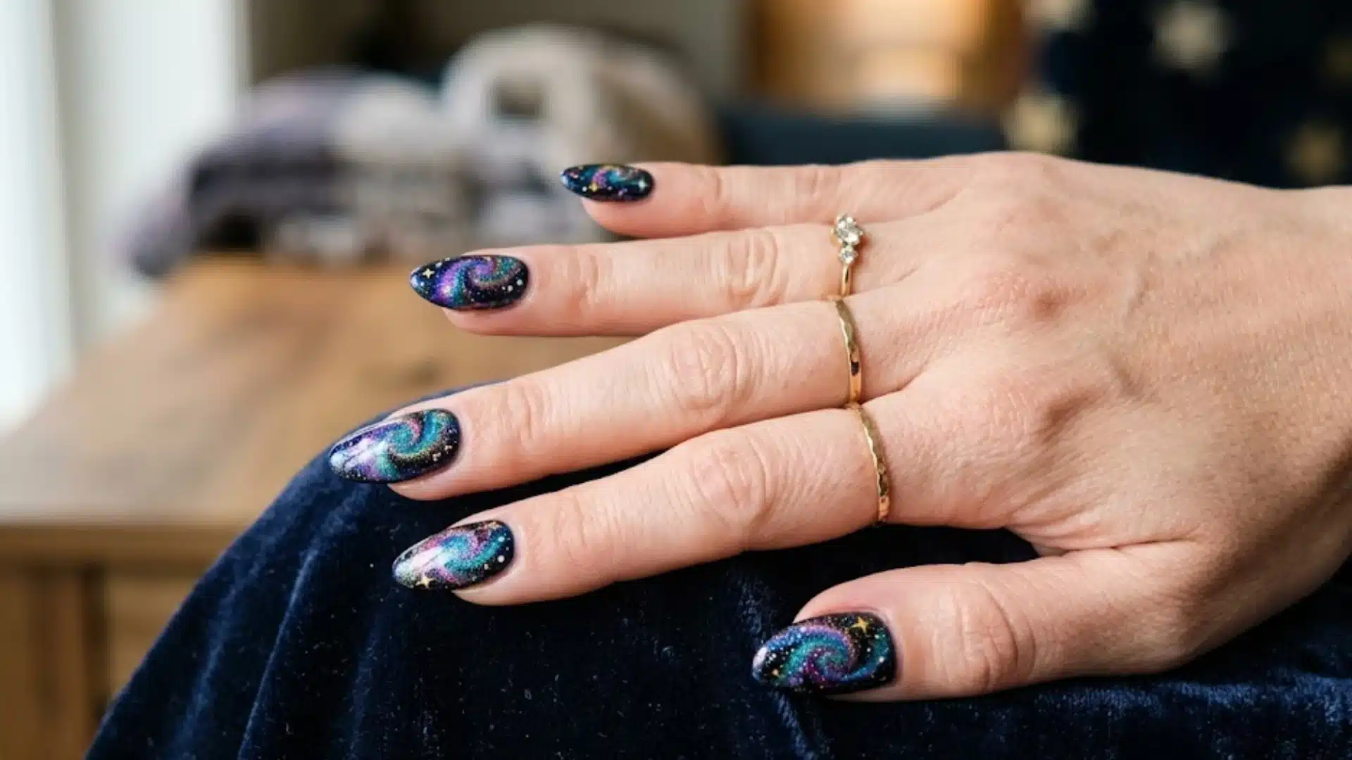 Cosmic Swirl Nails featuring galaxy swirl nail art, multicolor shimmer on dark base, glossy finish, cozy indoor setting