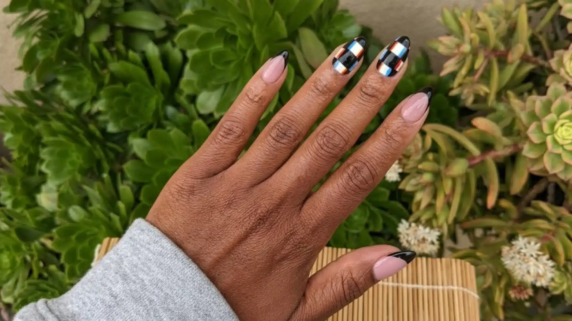 Digital Glitch Nails featuring black French tips and colorful geometric accent nail, glossy finish, outdoor natural background
