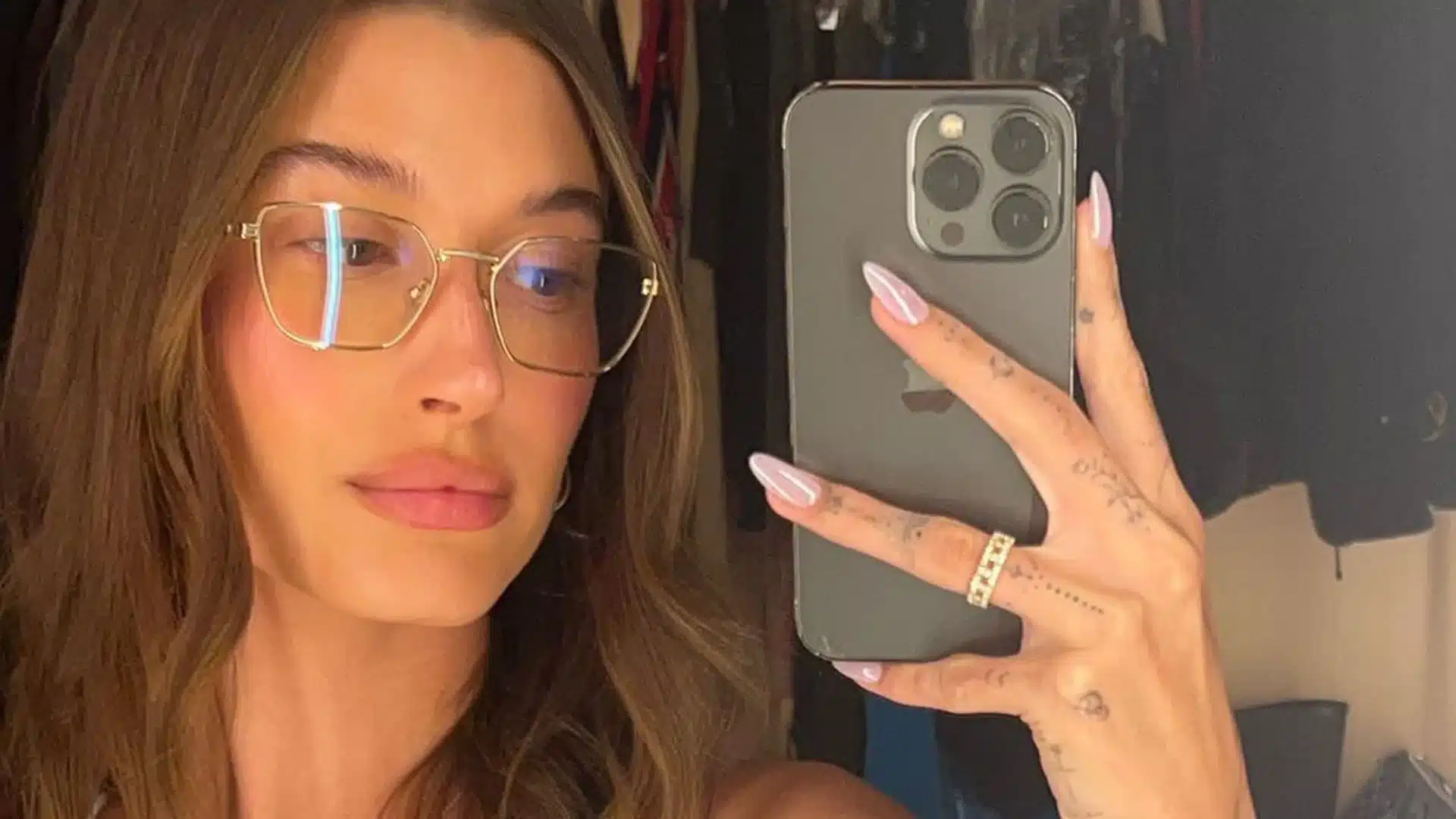 Hailey Bieber inspired glossy pink glazed donut nails in a mirror selfie